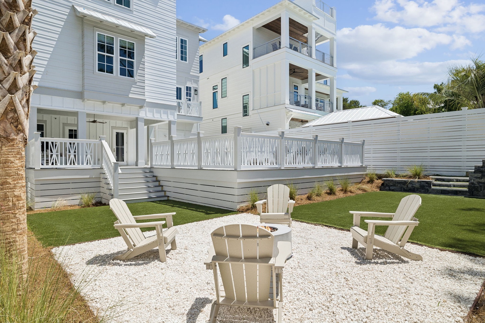 Elegant coastal retreat with pristine white architecture, featuring multiple levels of wraparound balconies and a beautiful landscaped yard.