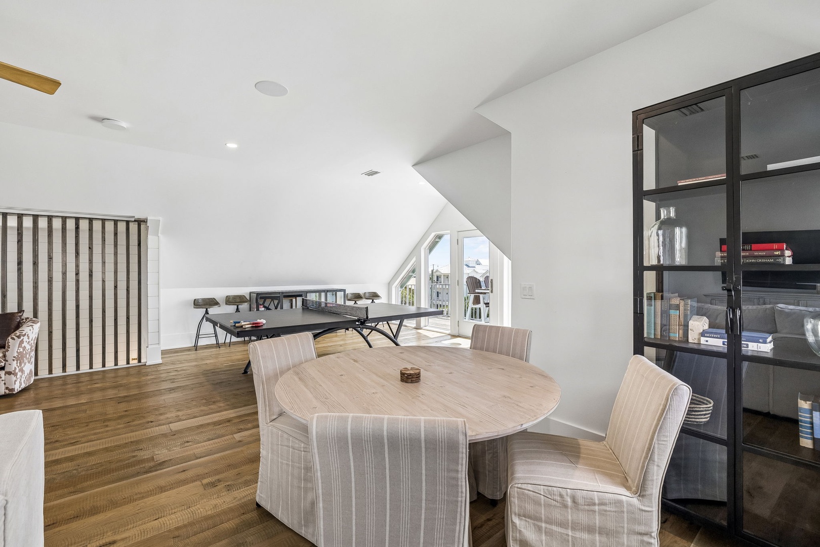 Your private loft retreat opens into a bright, airy space with vaulted ceilings, warm wood floors, and dual areas for dining and playing games—perfect for quality time together under a soft natural glow.