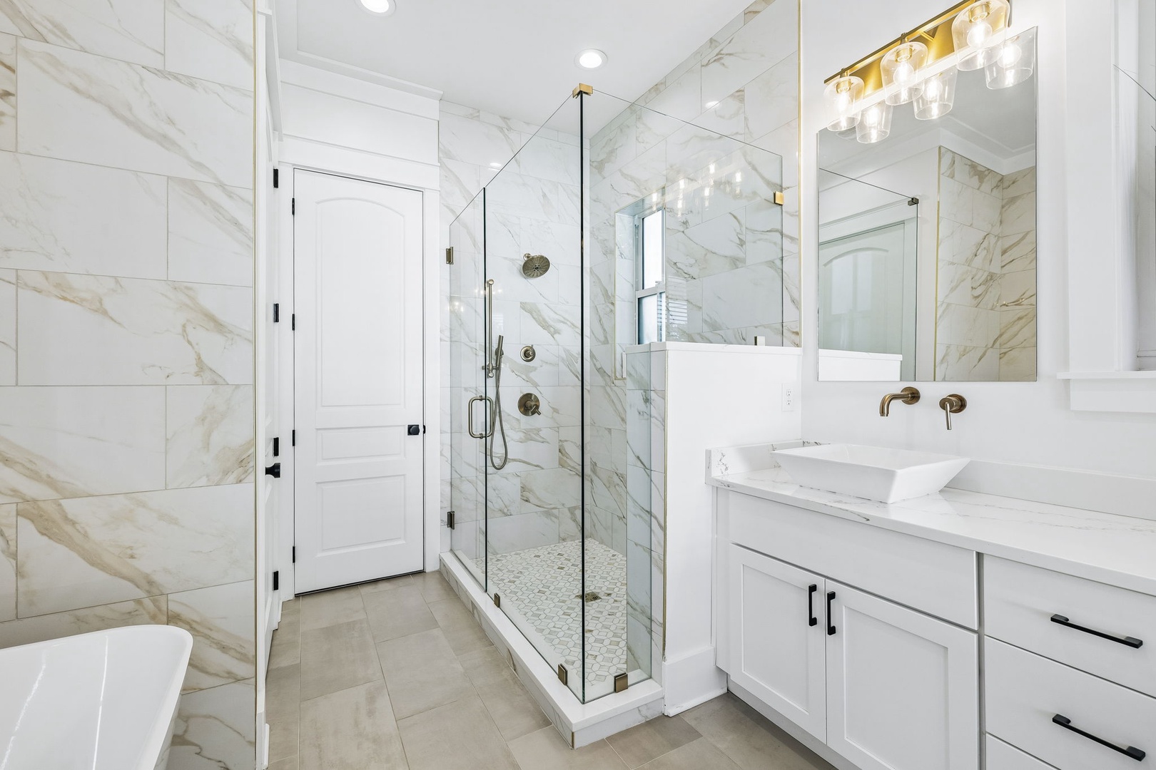Step into a spa-like retreat with gleaming marble walls, a sleek walk-in shower, and elegant gold fixtures that make every moment feel indulgent.