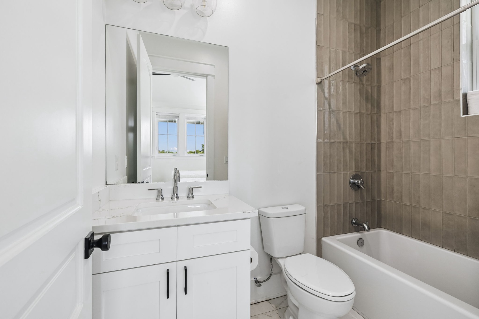 Your private bathroom features a modern vanity with marble countertop, a refreshing tub/shower combo with wood-look tile surround, and crisp white finishes throughout.