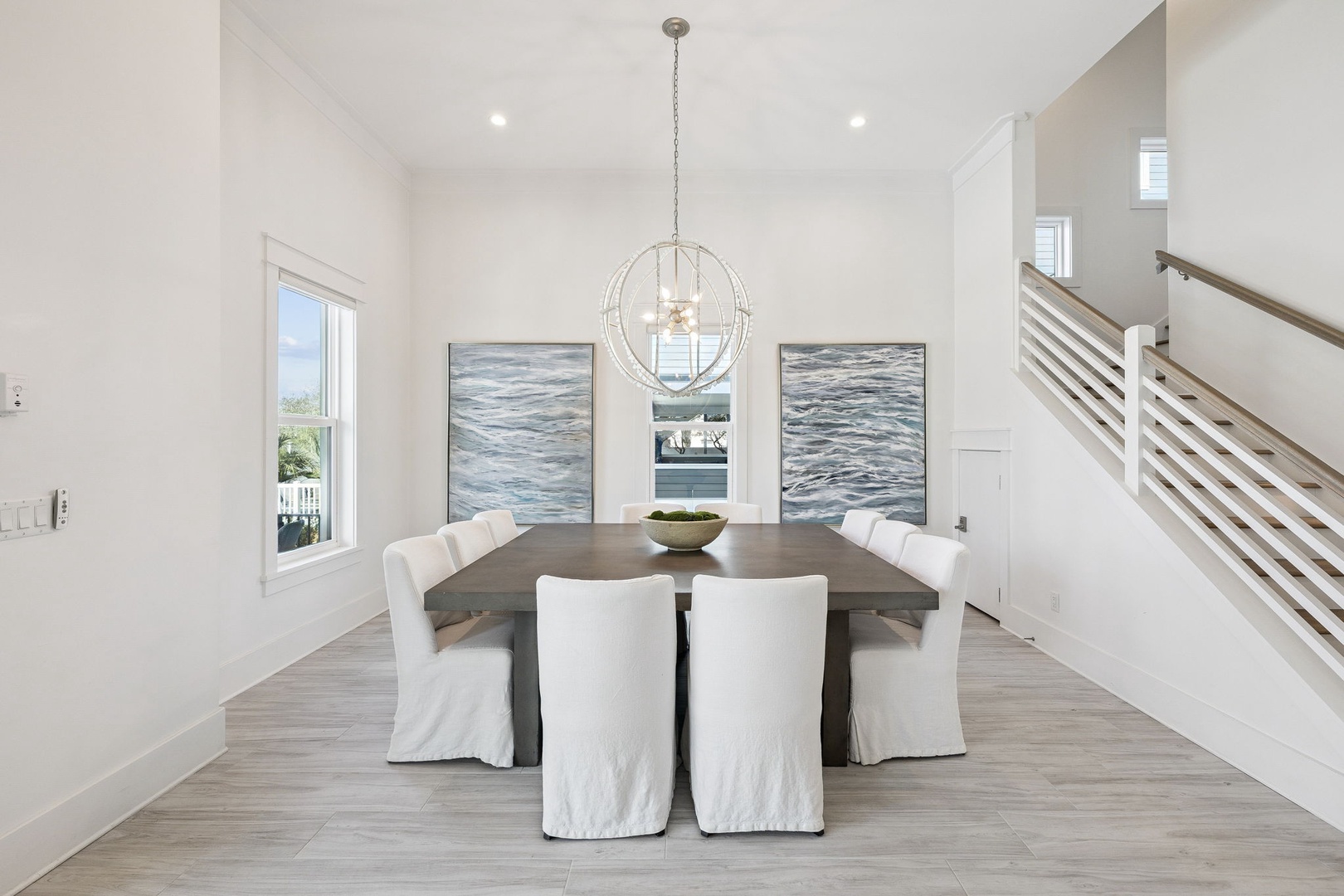 Your elegant dining space features a stunning table for six beneath coastal-inspired artwork, where memorable meals unfold in sophisticated comfort.