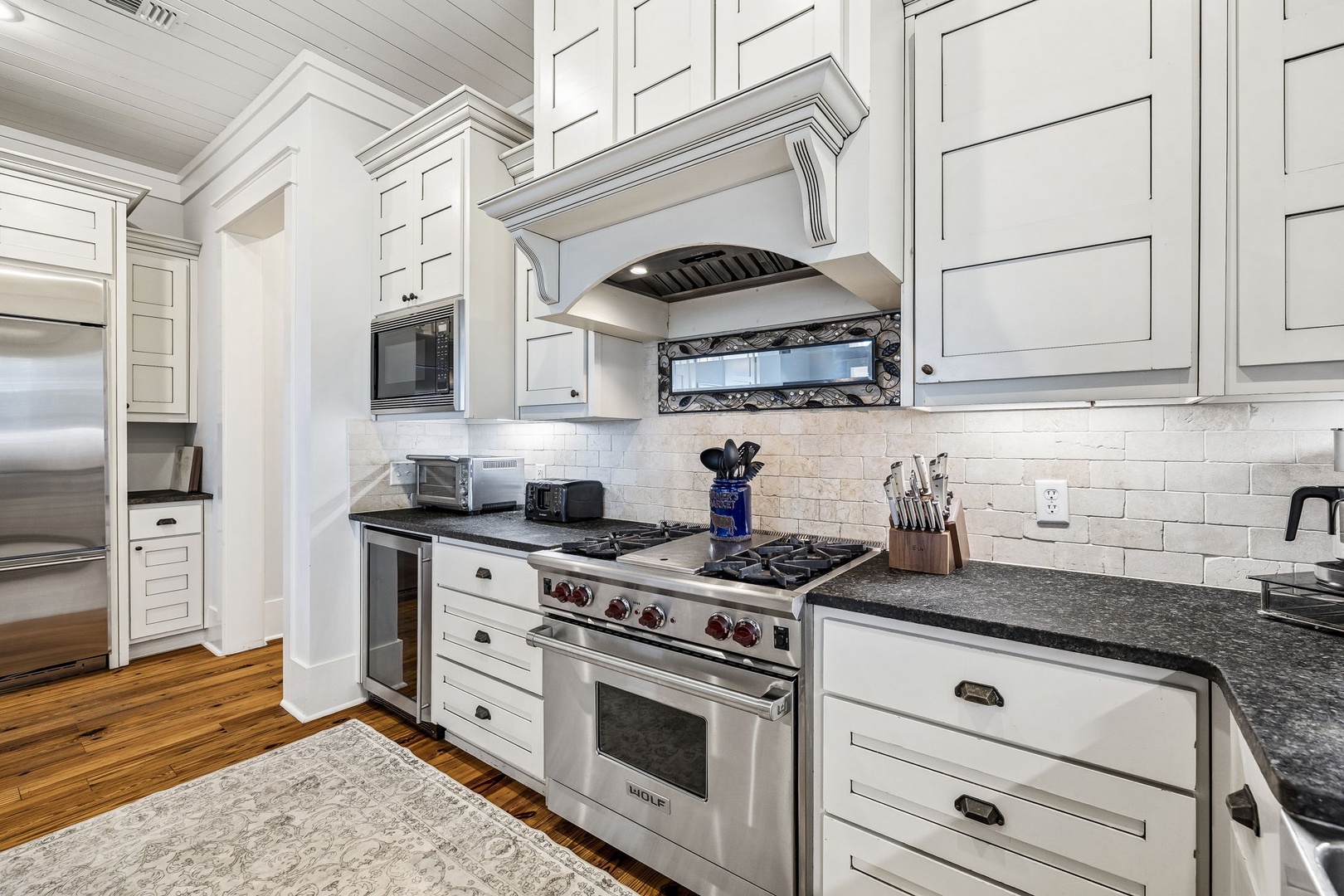 Your chef's kitchen awaits—gleaming granite counters, professional-grade gas range, and pristine white cabinetry all ready for you to create memorable meals during your stay.