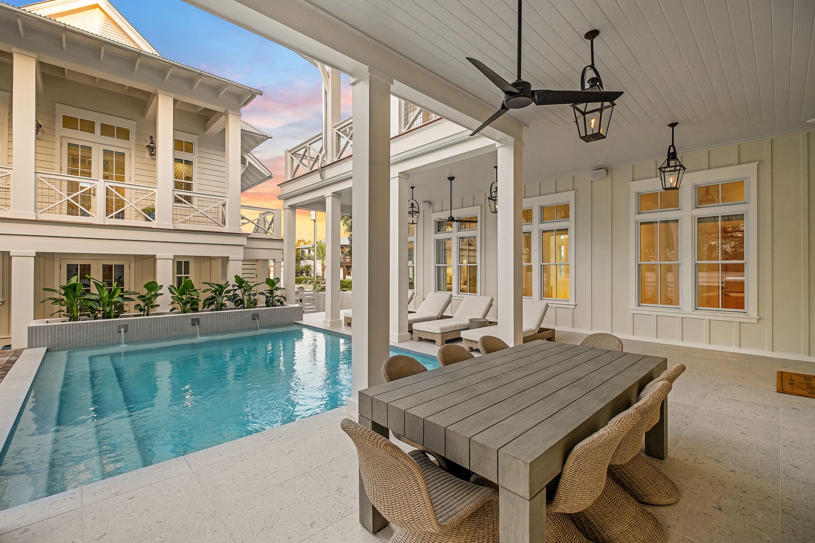 This elegant covered outdoor dining area offers poolside seating under soft lantern lighting, perfect for your morning coffee or evening gatherings. The classic coastal design creates a seamless flow between indoor comfort and outdoor relaxation.
