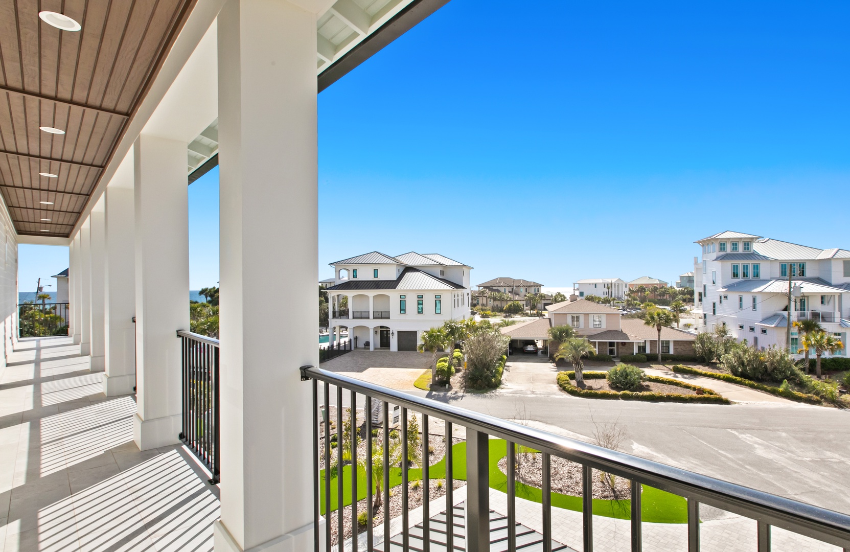 This covered balcony overlooks a peaceful residential neighborhood of coastal homes with a view toward the ocean, creating a welcoming arrival setting for your stay.