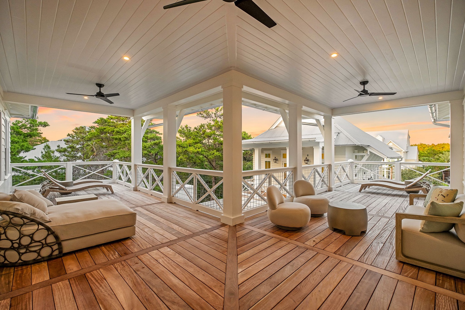 A spacious covered deck with comfortable loungers and seating invites you to unwind in style, framed by warm wood tones and gentle breezes beneath elegant vaulted ceilings.