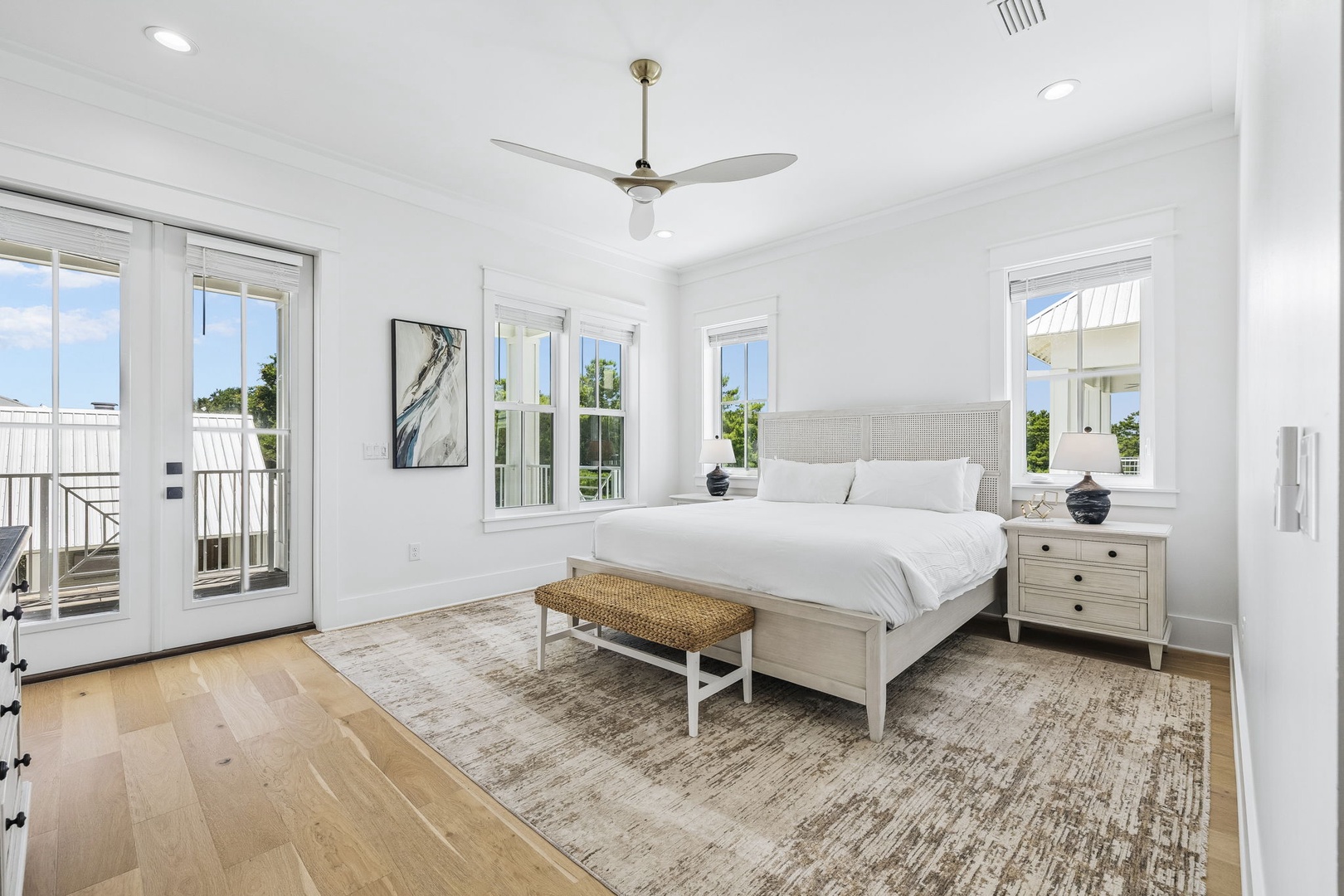 Settle into your serene retreat where crisp white linens invite restful sleep, and natural light pours through windows that frame glimpses of greenery. The ceiling fan keeps your space comfortable year-round.