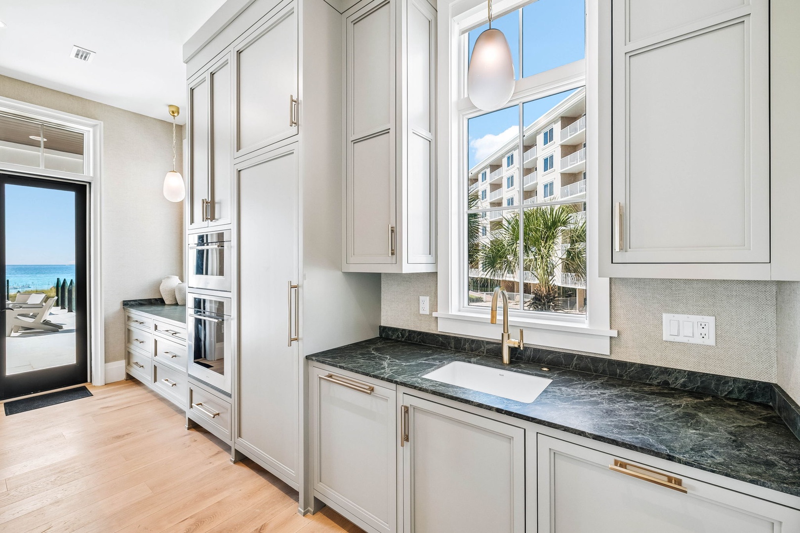 Step into your elegant kitchen with custom cabinetry, sleek granite counters, and gold fixtures—where every detail invites you to savor the art of cooking and coastal living.