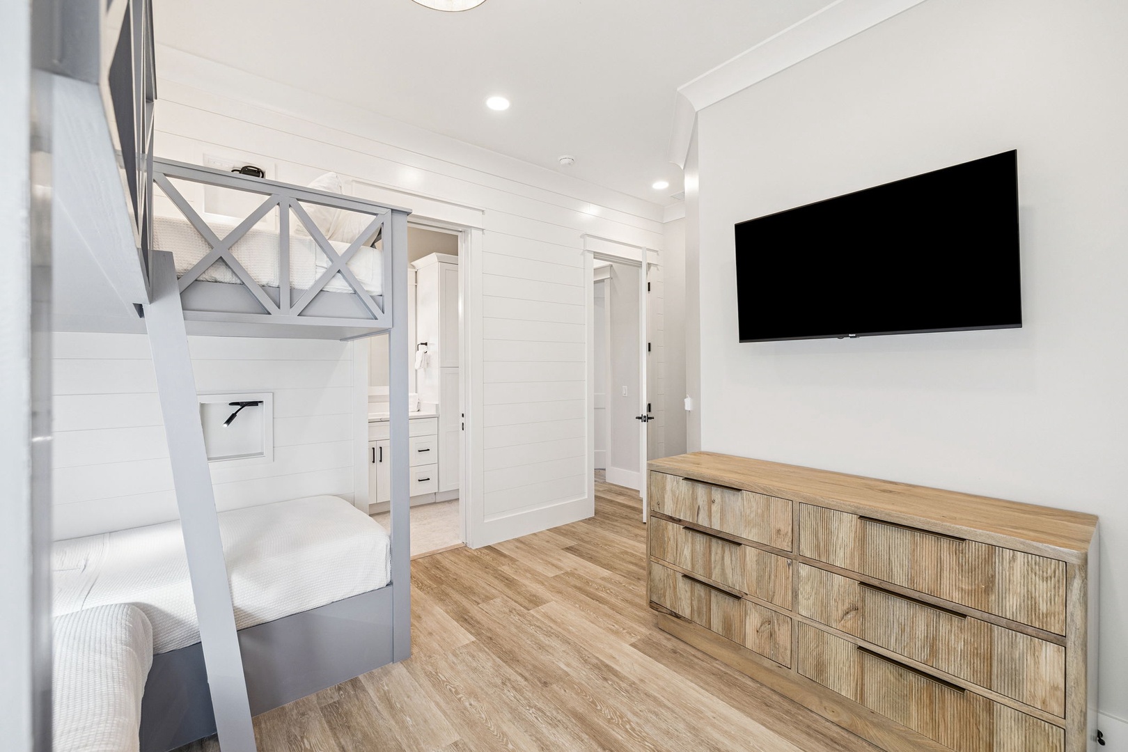 Your stylish bunk room features crisp white walls, warm wood floors, and a wall-mounted TV for cozy evenings.
