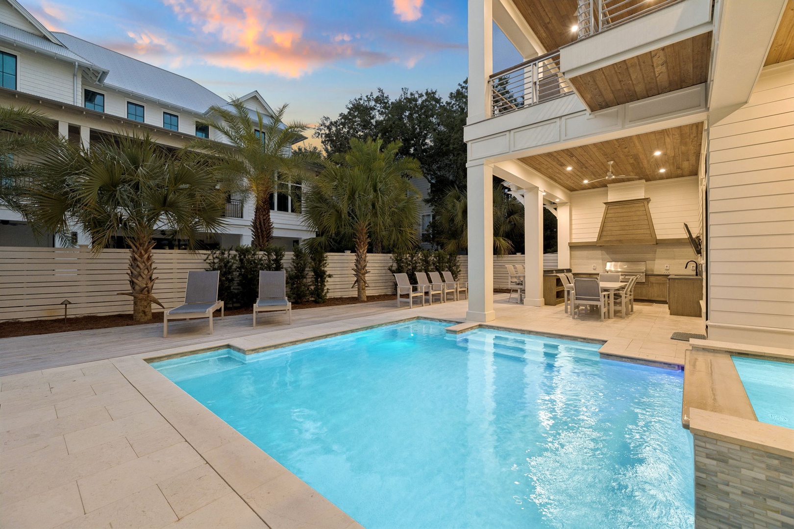 Elegant pool area with outdoor kitchen creates perfect evening ambiance for relaxation and entertaining.