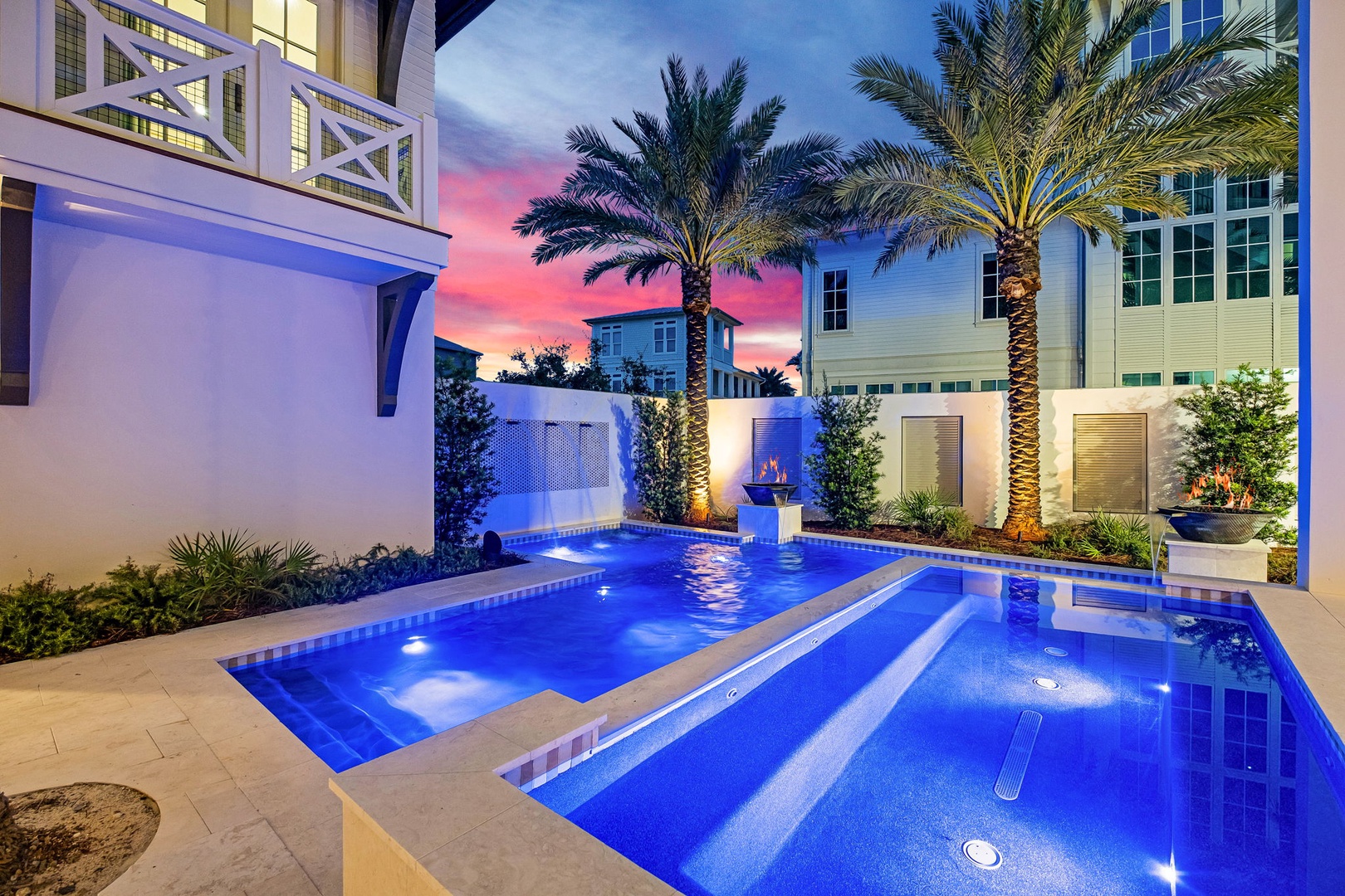 A stunning private courtyard where glowing blue waters invite evening swims beneath swaying palms and a painted twilight sky.