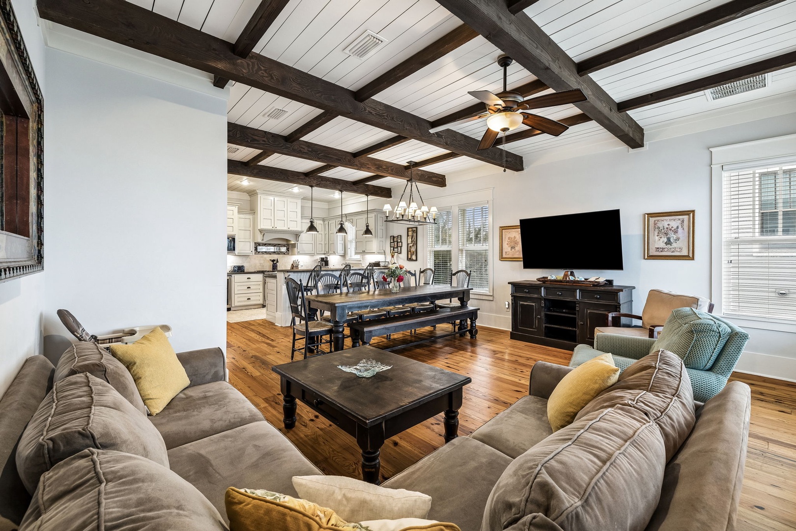 Gather under stunning exposed wood beams in this spacious open living area, where your group can relax on plush seating, share meals at the long farmhouse table, and unwind together with rustic charm all around.
