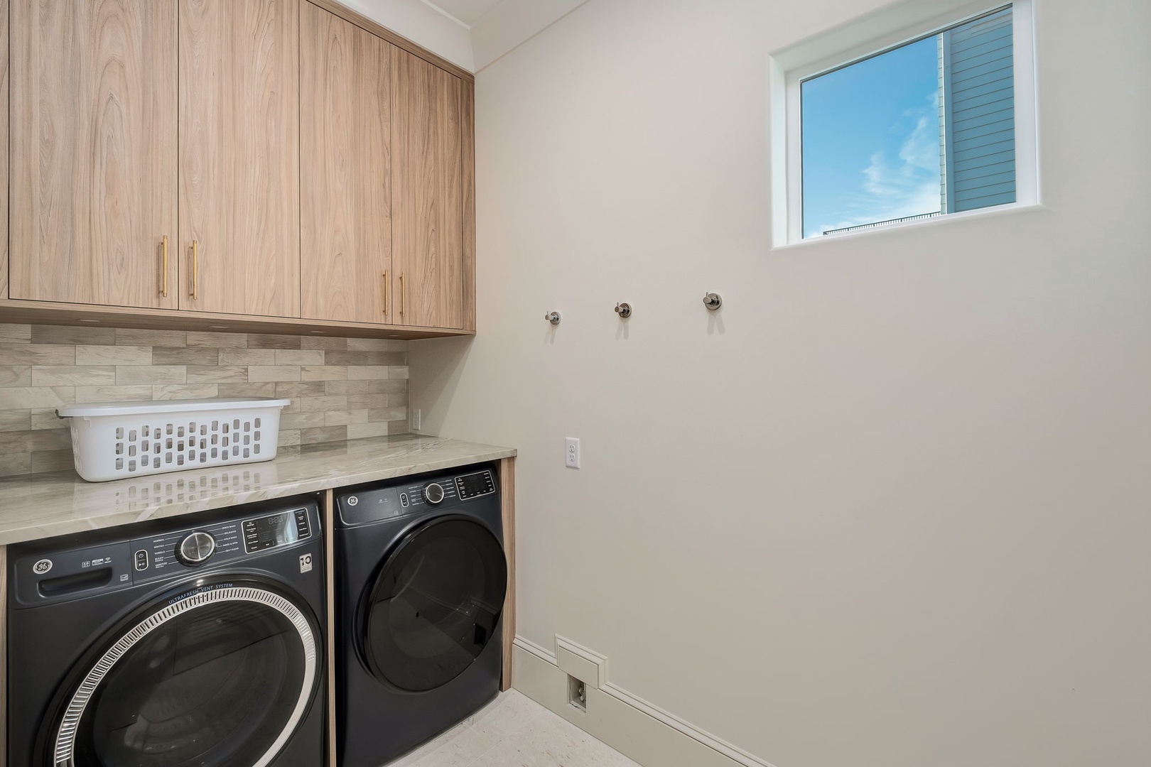 Your dedicated laundry room makes keeping fresh linens and clothes effortless, with modern machines and bright natural light streaming through the window above.