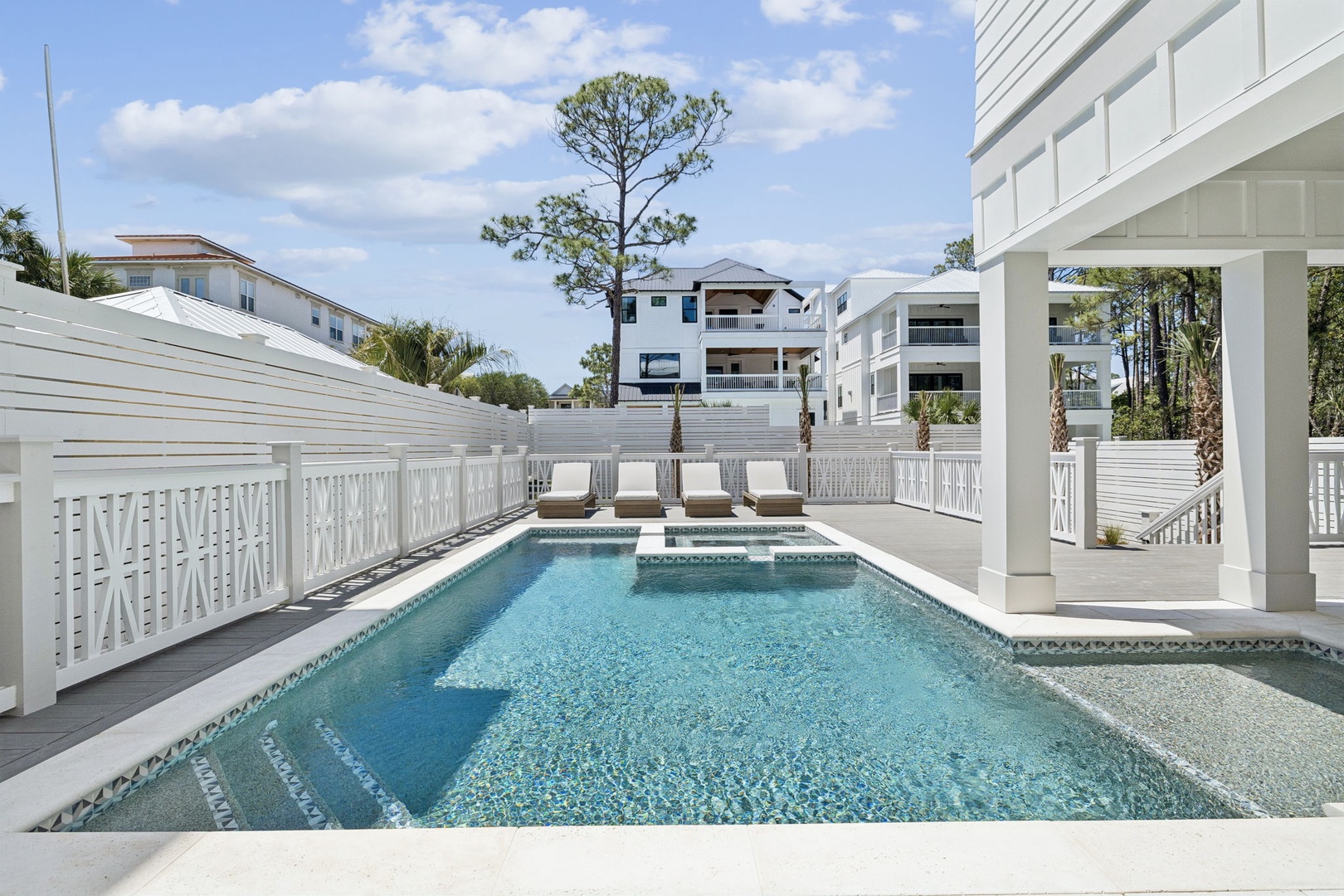 Dive into your private oasis where crystal-clear waters sparkle beneath blue skies, surrounded by elegant white architecture and peaceful lounging areas.