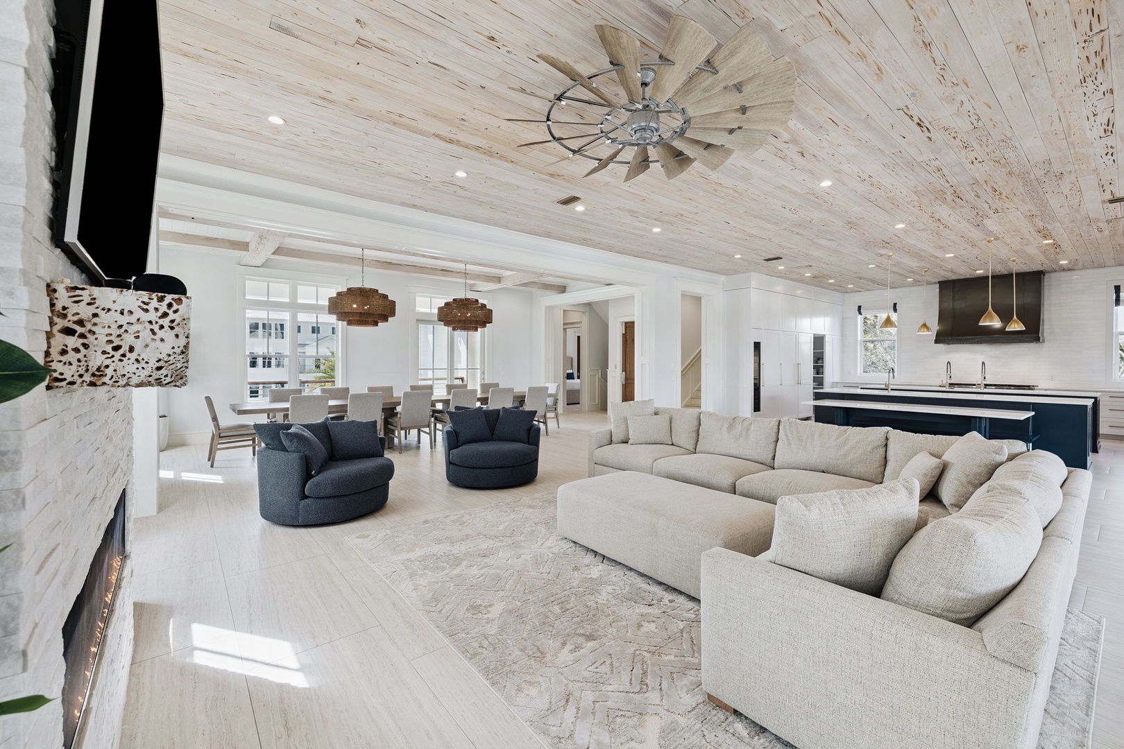 Sink into plush sectional seating beneath stunning whitewashed wood ceilings. Your open-concept haven flows seamlessly from cozy fireplace to gourmet kitchen.