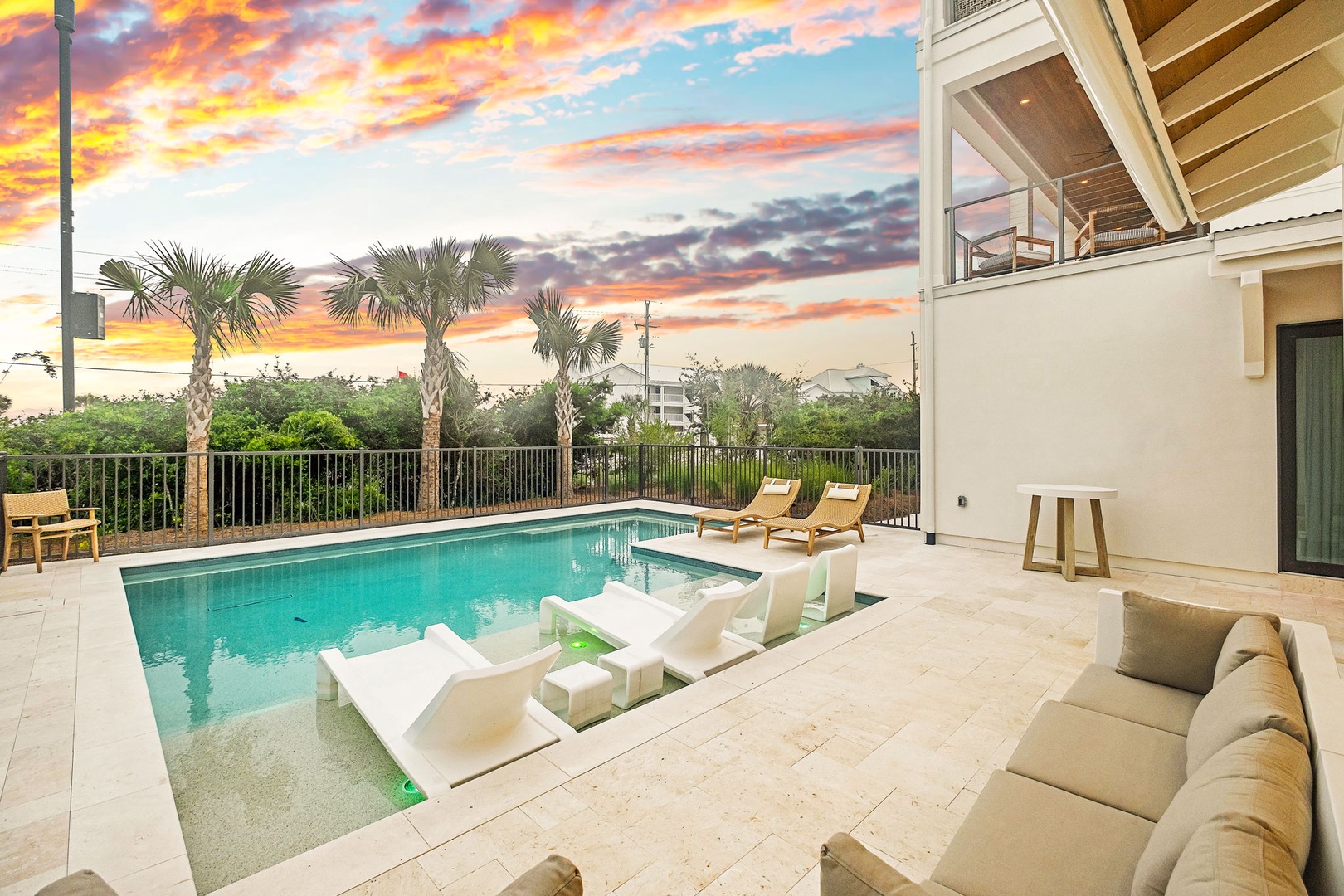 The property features a private pool, modern patio, tropical landscaping, and stunning sunset views from the outdoor living space.
