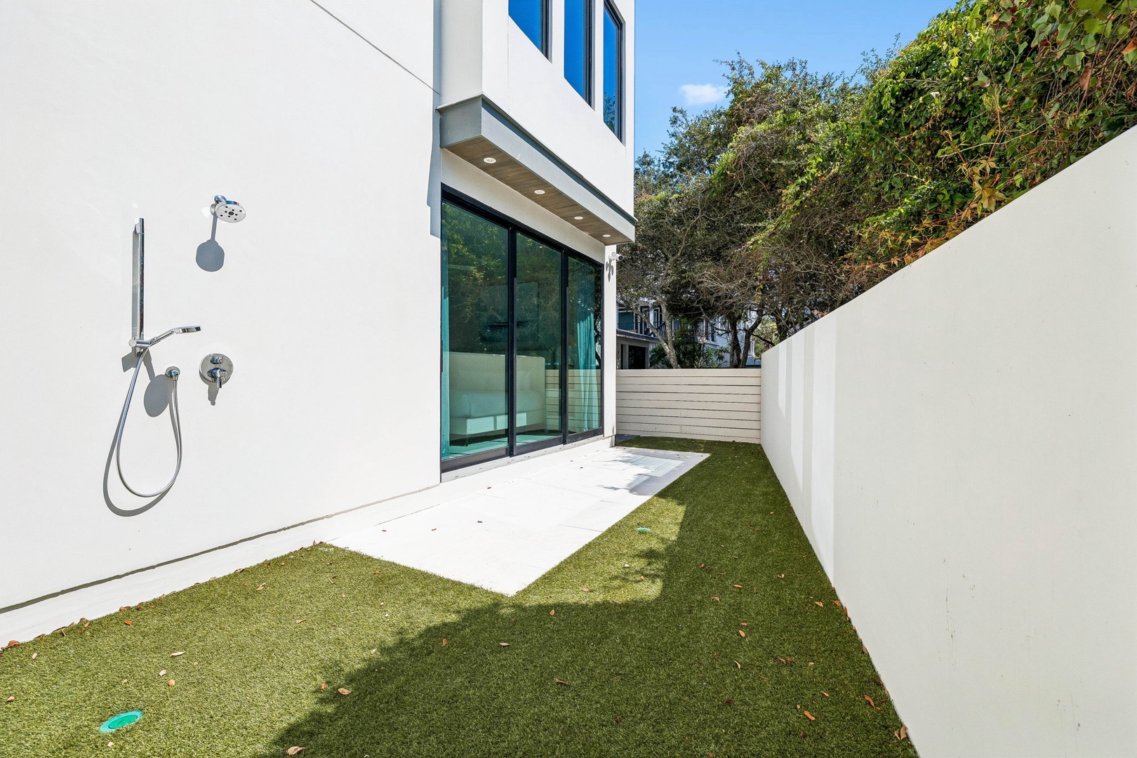 A private outdoor courtyard with an outdoor shower, perfect for rinsing off after a day at the beach. Clean lines, fresh greenery, and direct access from your suite.