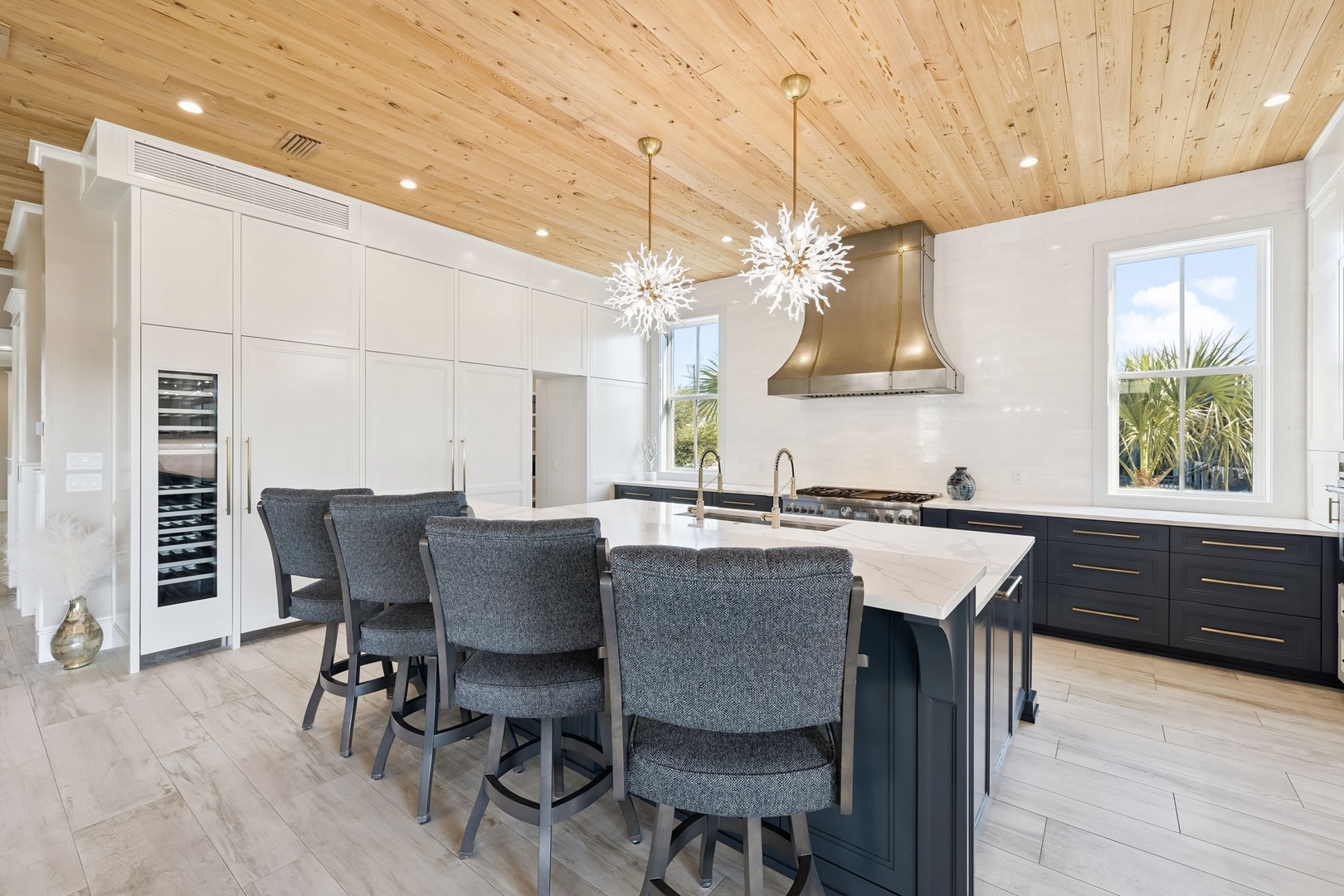 Your gourmet kitchen features sleek white cabinetry, a spacious island with seating, and stunning wood ceilings that create the perfect space for cooking and gathering.