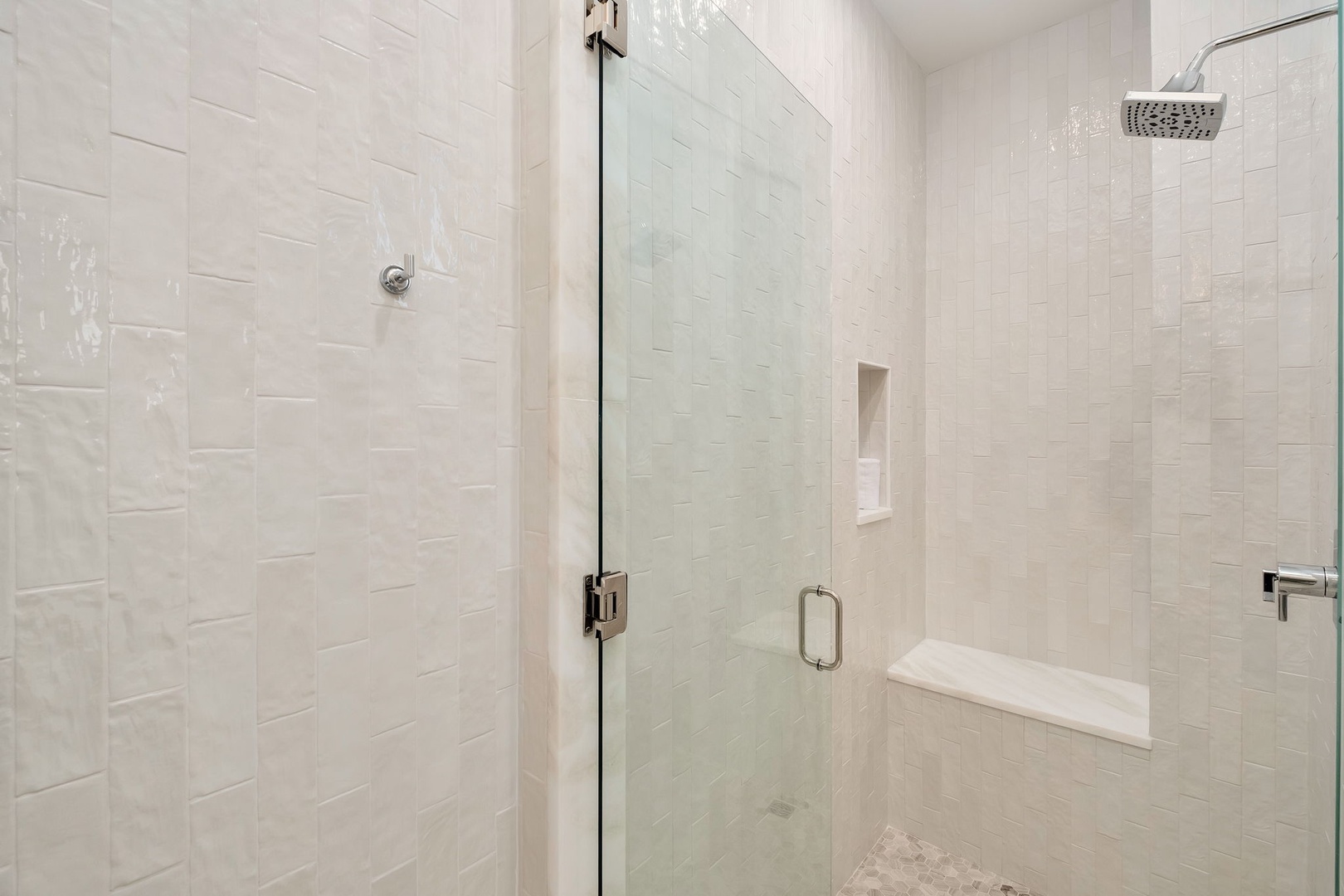 Step into your private spa-like retreat with elegant textured tile, a spacious walk-in shower with dual fixtures, built-in seating, and sleek glass enclosure for your ultimate comfort.