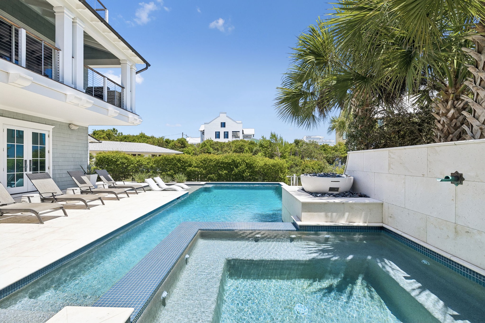 A sparkling pool and integrated spa await you beneath swaying palms, with loungers lining the sun-drenched deck for ultimate relaxation.