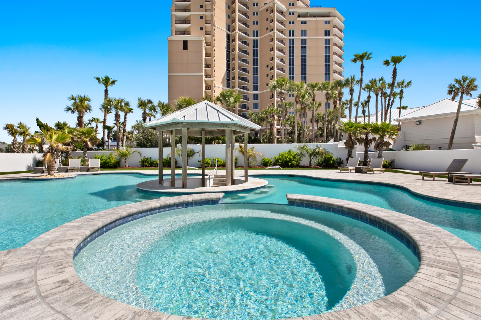 The resort-style pool features crystal-clear waters, a relaxing hot tub, and swaying palms under endless blue skies—your tropical escape awaits.