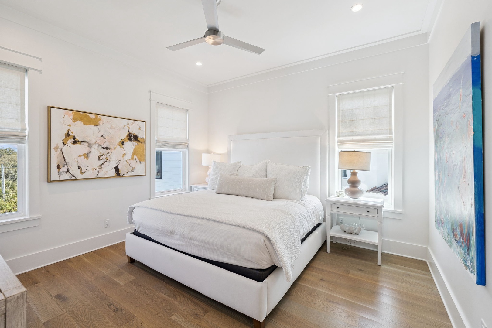 Sink into luxury in your serene bedroom with crisp linens, warm wood floors, and natural light streaming through multiple windows.