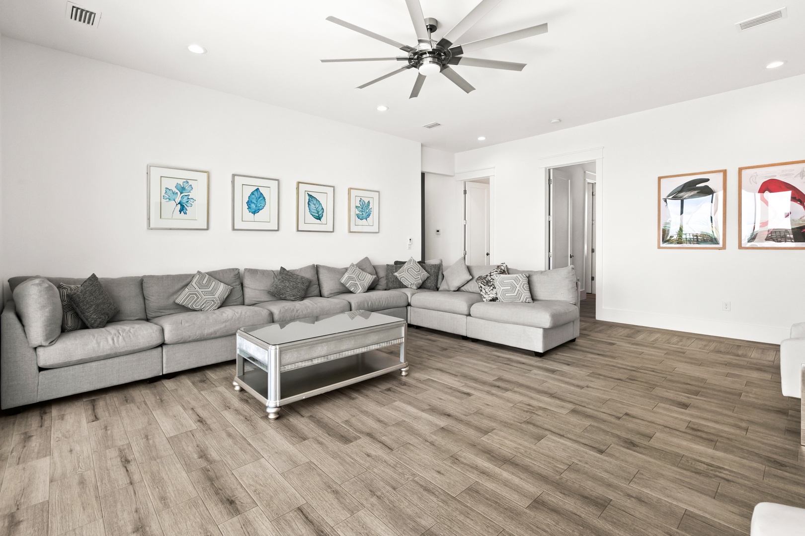 Sink into plush sectional seating and enjoy the airy, modern living space designed for your comfort, complete with stylish ceiling fan and warm wood-look floors that flow seamlessly throughout.