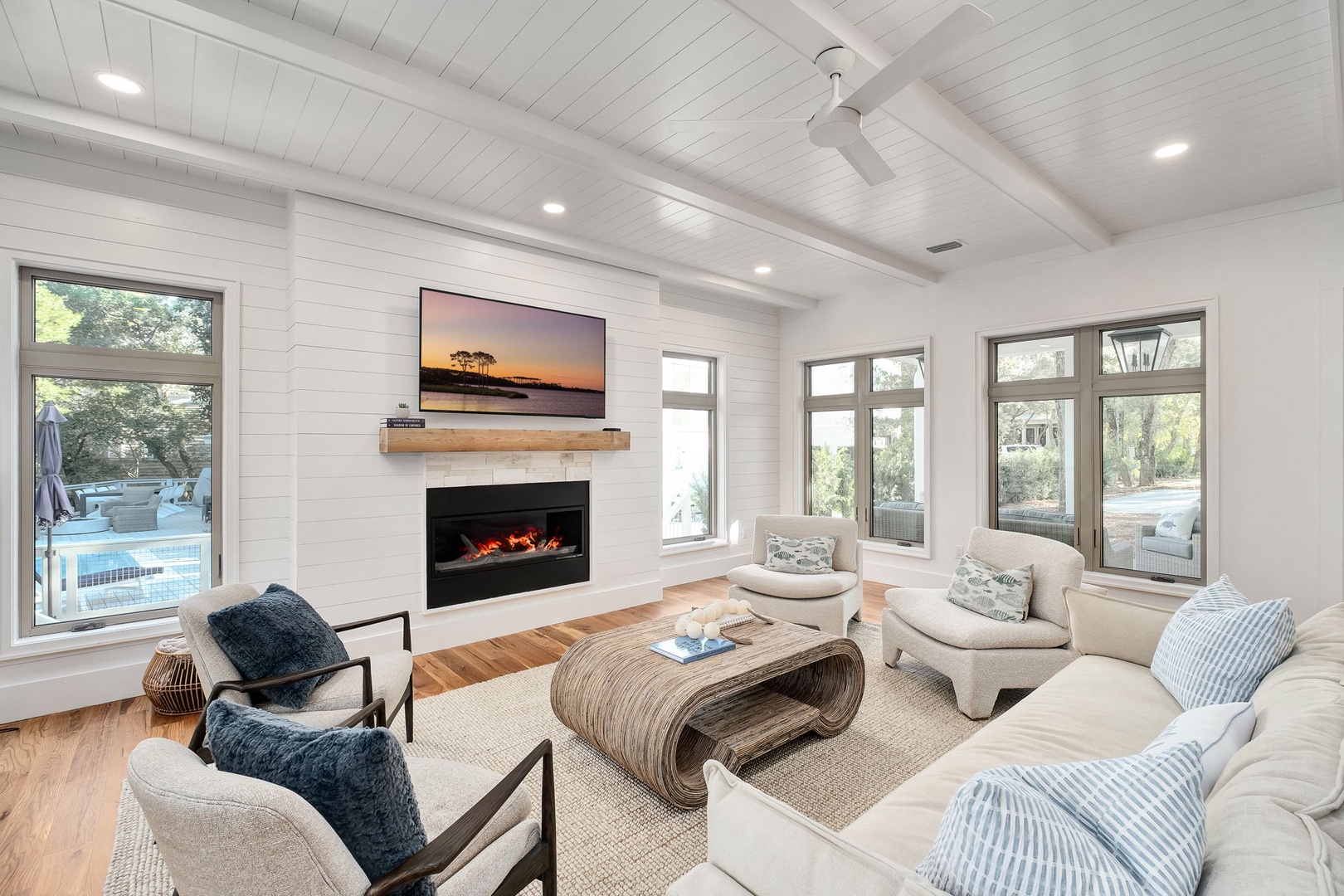 Sink into plush seating by your modern fireplace, where ceiling beams frame peaceful moments and pool views.