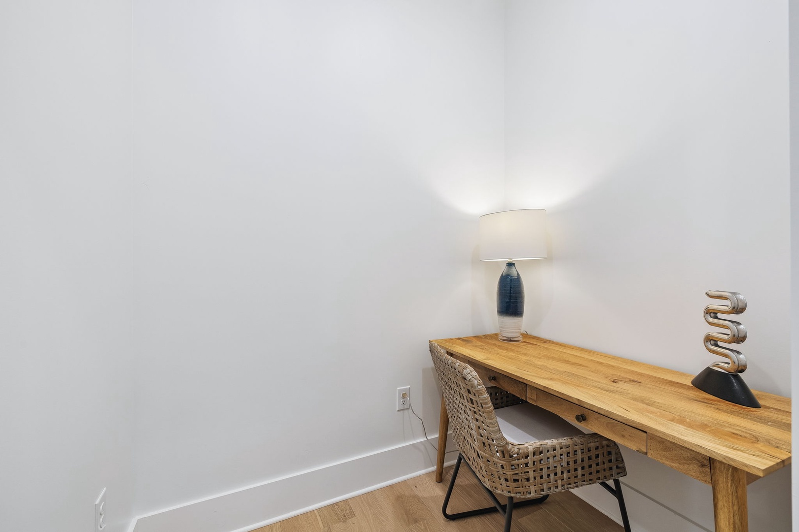 Your quiet nook awaits—complete with a warm lamp, modern desk, and woven chair. It's the perfect spot to catch up on work or jot down your travel memories.