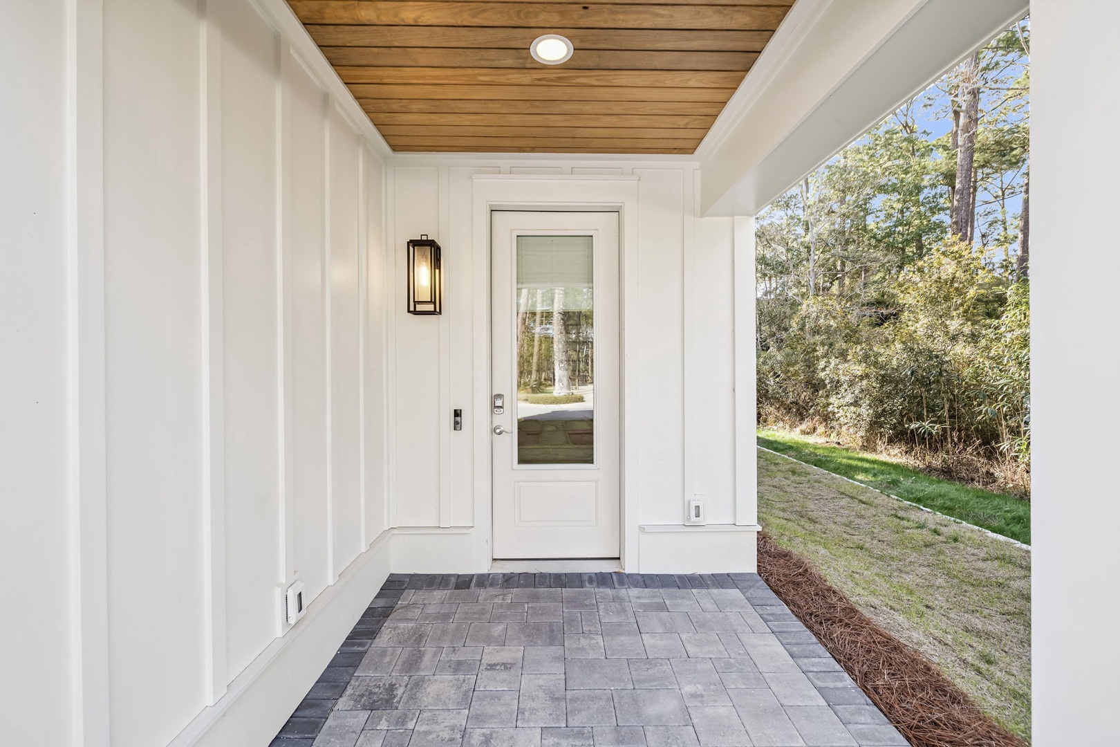A welcoming front entrance with modern white door, warm wood ceiling, and charming outdoor lighting sets the tone for your arrival.
