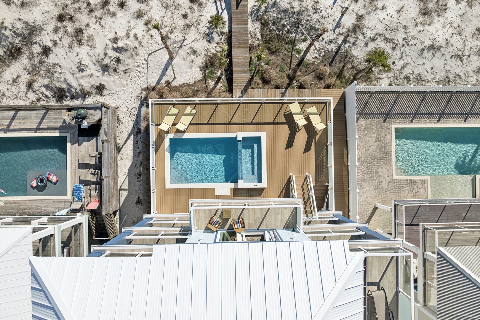 Aerial view showcasing modern beachfront accommodations with private pools and pristine white sand surroundings.