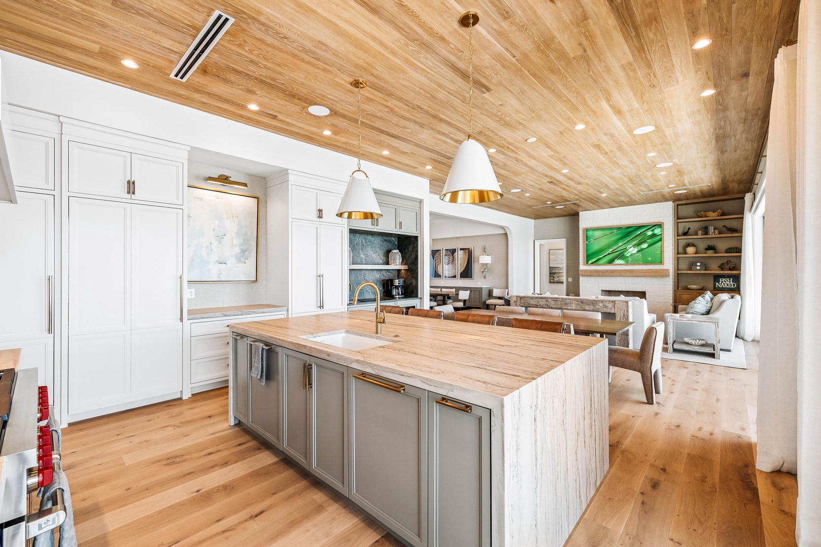 Your chef's kitchen seamlessly flows into the living and dining areas, featuring warm wood ceilings, elegant pendant lighting, and a spacious island perfect for gathering with loved ones.