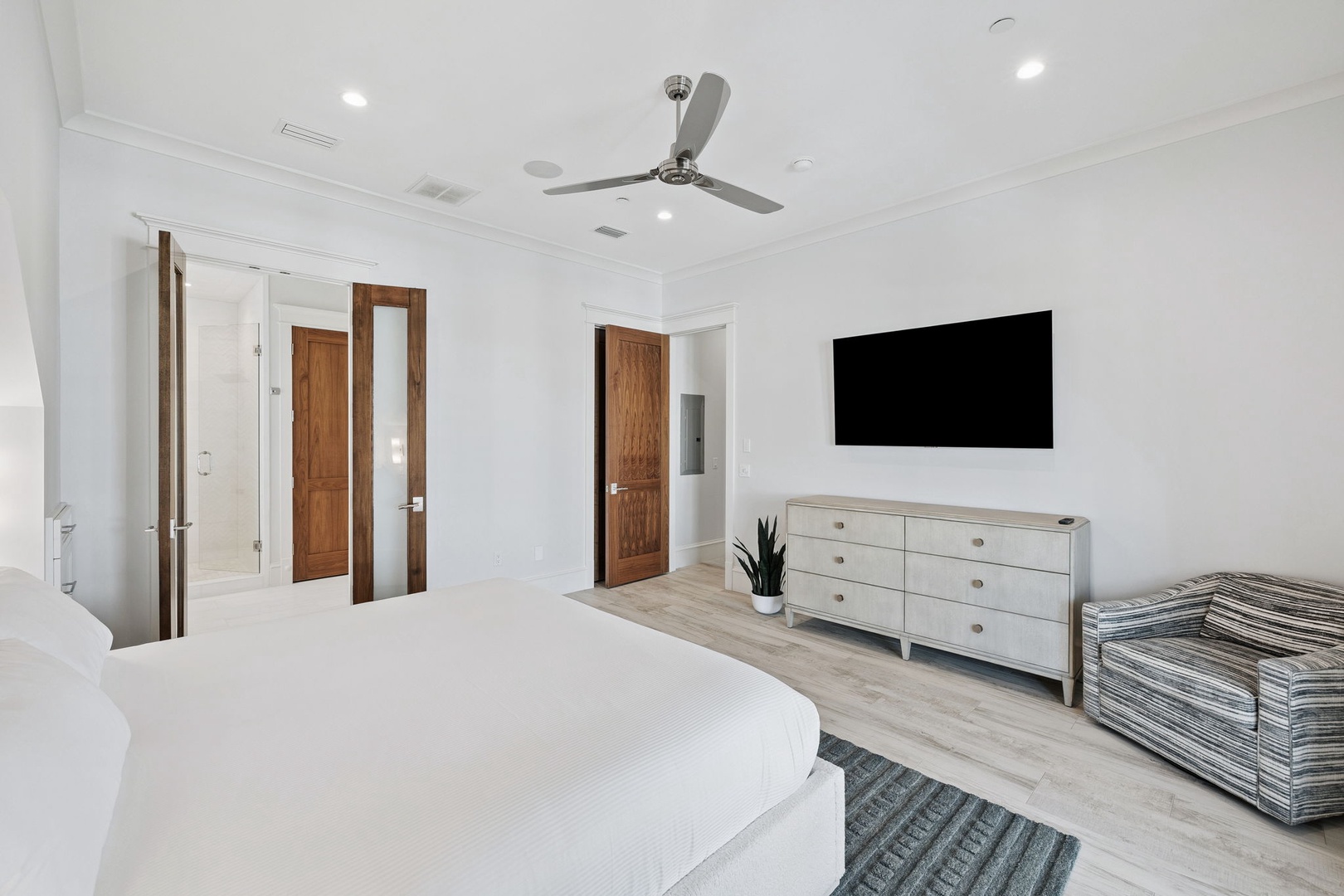 Unwind in your serene master bedroom, featuring a plush bed, smart TV, and stylish furnishings in a bright, airy space designed for ultimate relaxation.
