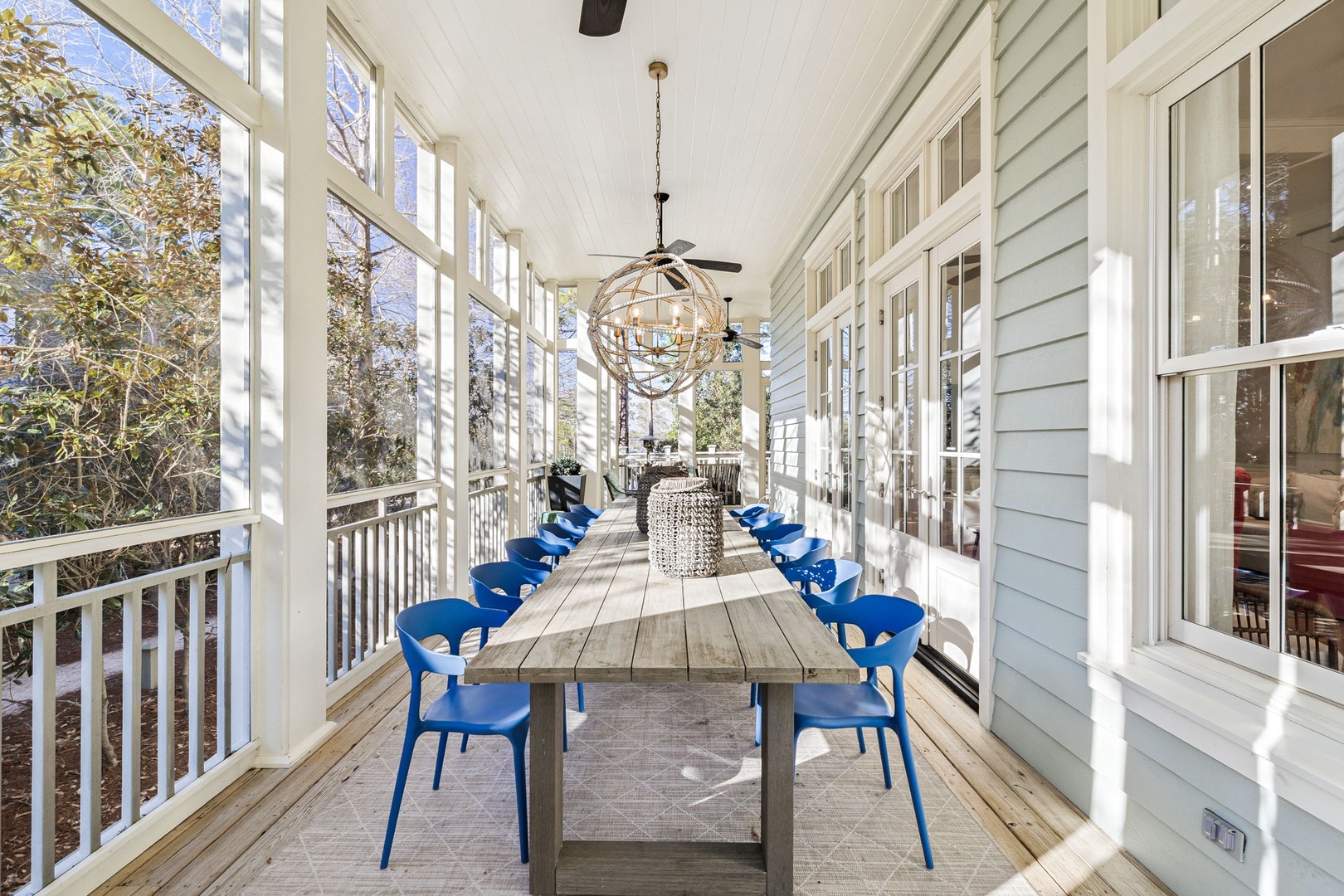 Gather your group for memorable meals on this gorgeous screened porch, where sunlight dances through windows and vibrant blue chairs invite long conversations.