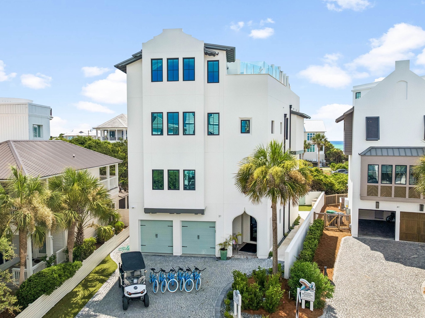 Coastal rental property featuring modern architecture with turquoise accents, ocean views, bicycles, and a golf cart for exploring the neighborhood.