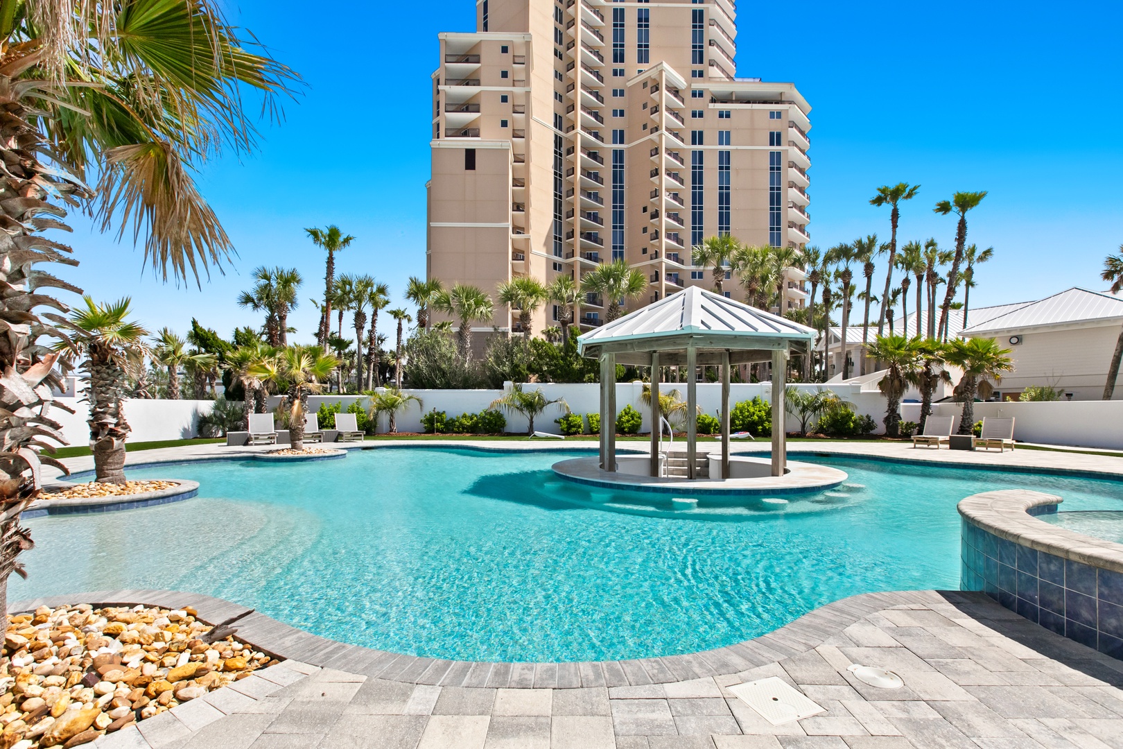 This beachside resort features a sparkling pool oasis surrounded by swaying palms and modern high-rise towers, creating a relaxing tropical escape right at your doorstep.