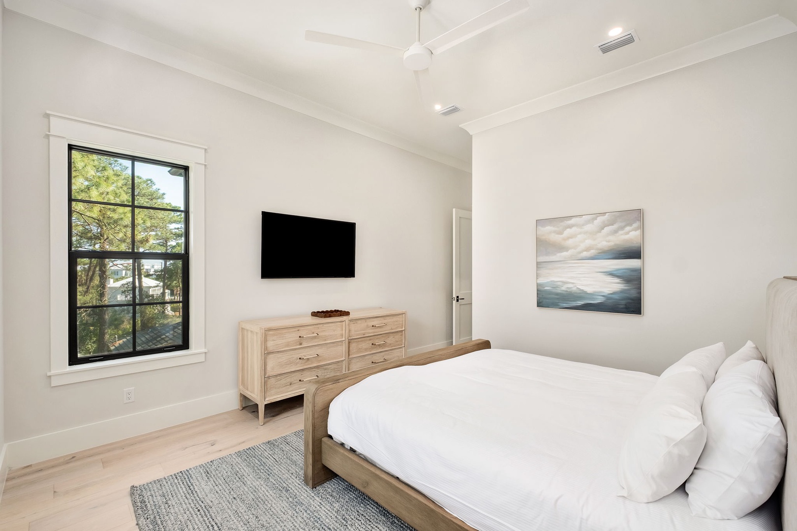 Sink into crisp white linens in your serene bedroom, where natural light flows through large windows and modern amenities await your relaxation.