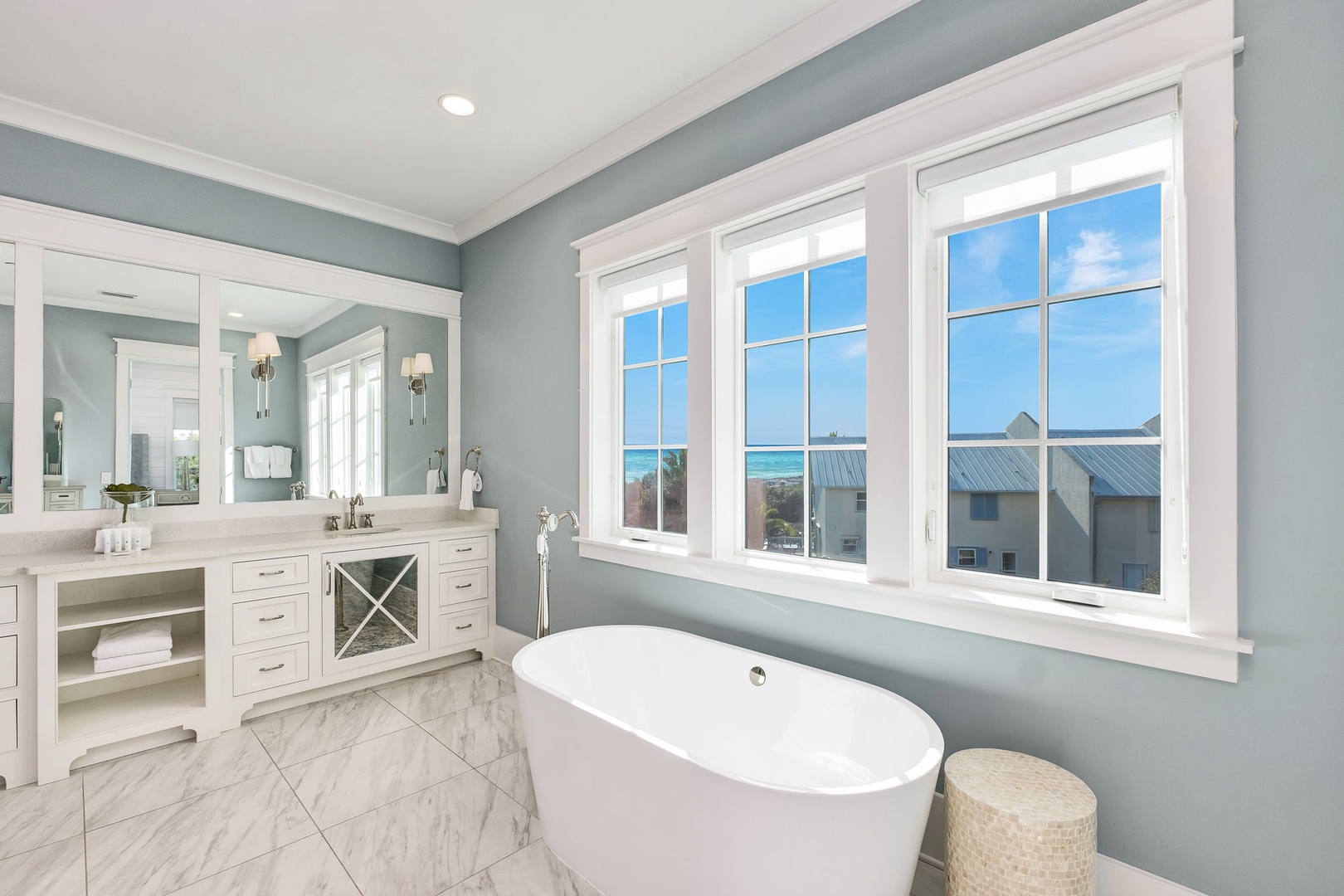 Unwind in your luxurious soaking tub while gazing at stunning ocean views through pristine windows in this serene coastal bathroom.
