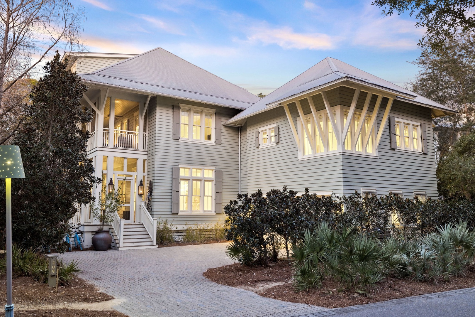 This elegant two-story coastal home features classic architecture with wrap-around porches and abundant windows, set among mature landscaping in a peaceful neighborhood.