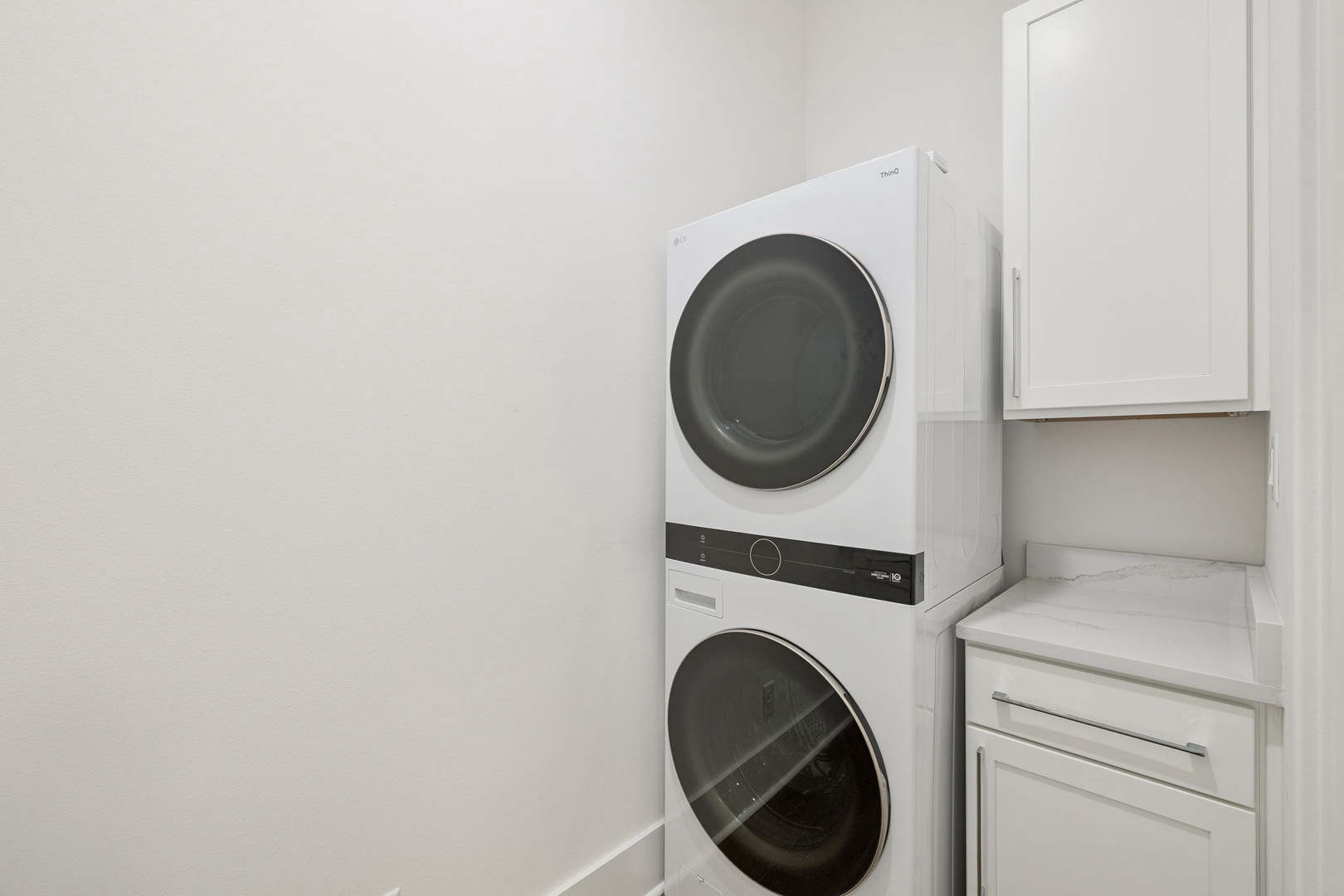 Keep your wardrobe fresh in this convenient in-unit laundry room with stacked washer and dryer plus storage.