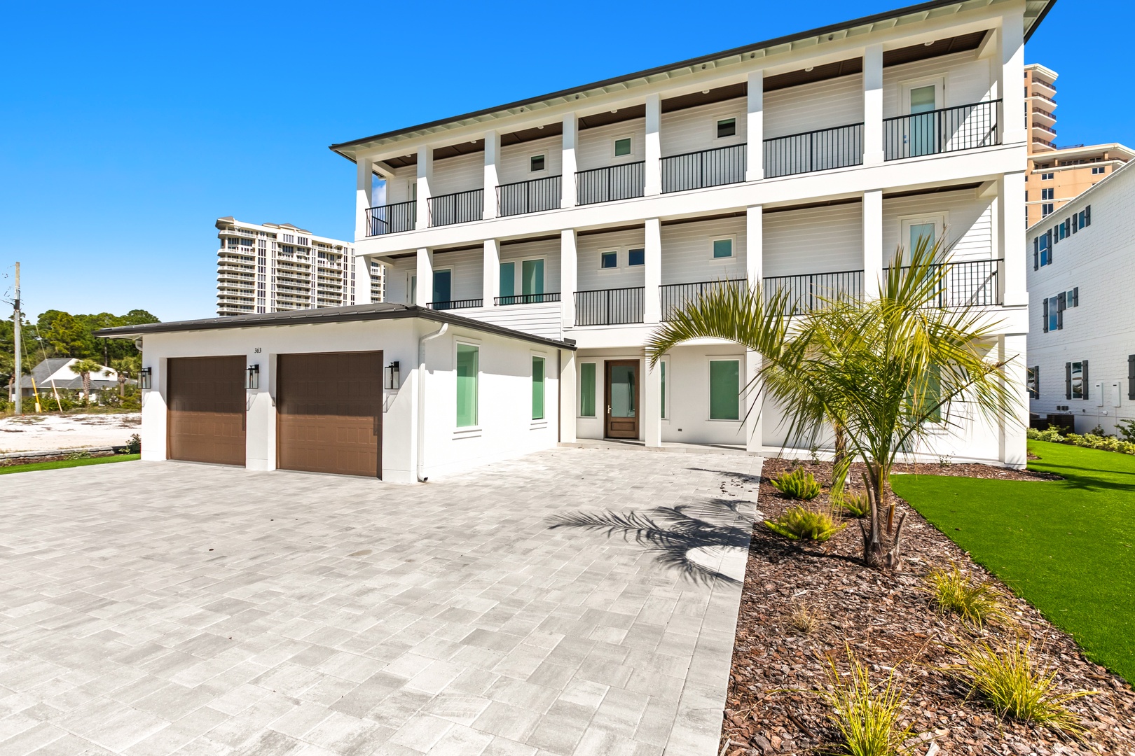 Striking coastal architecture meets modern elegance in this impressive three-story property, featuring spacious balconies and pristine landscaping just steps from nearby beach towers.