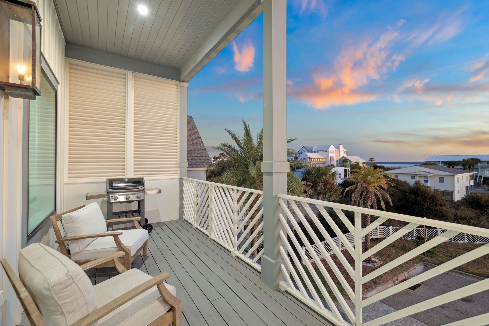Unwind on your private balcony with comfortable seating and BBQ grill, while colorful sunset skies paint the coastal horizon.