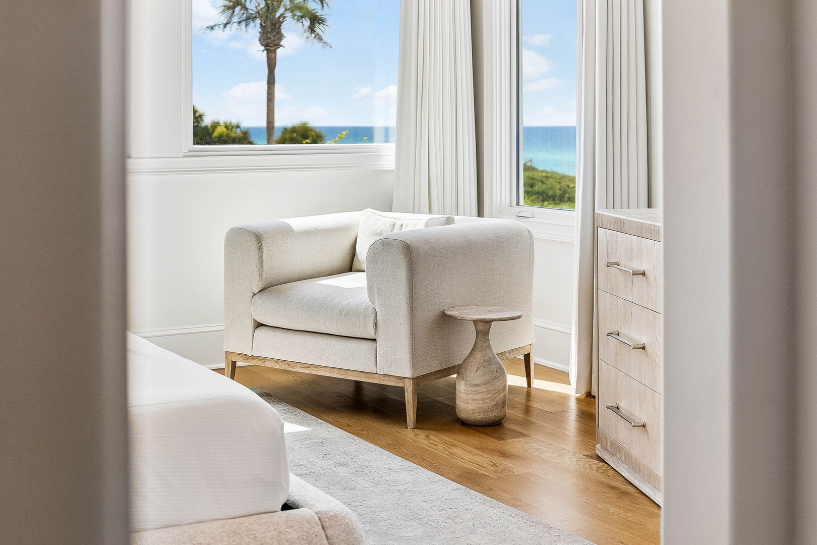 Settle into your peaceful reading nook where ocean breezes meet coastal elegance. Your private armchair with palm and sea views awaits your morning coffee or sunset unwind.