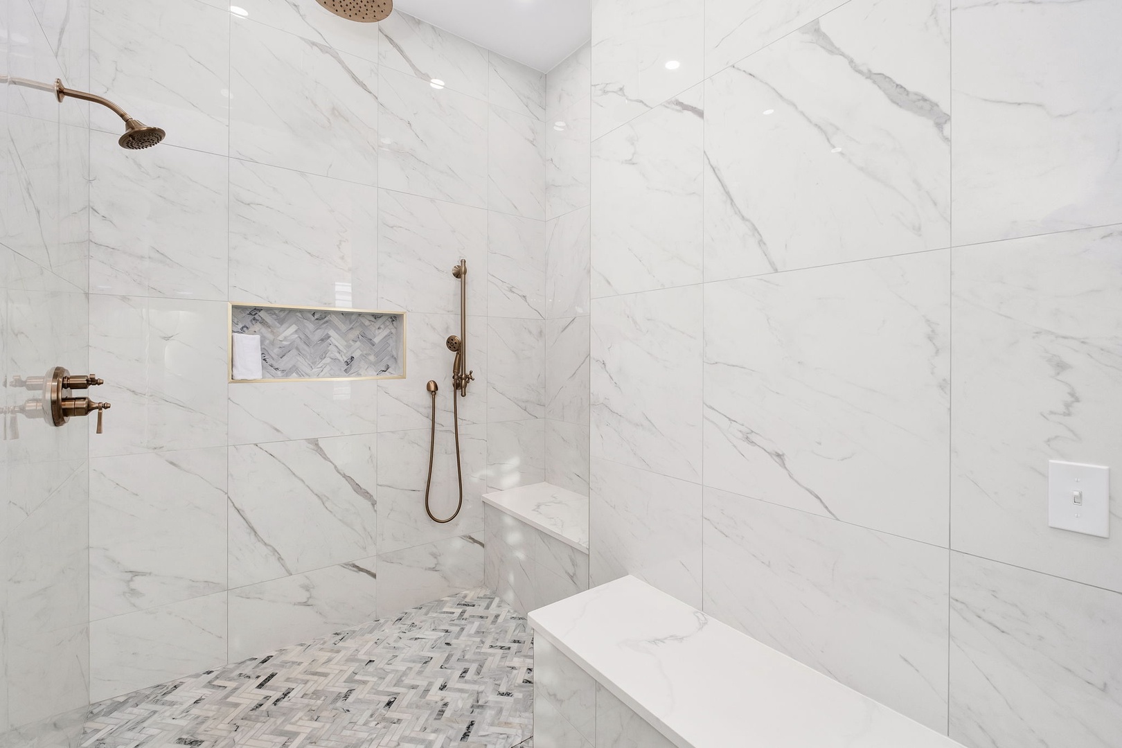 Step into your luxurious marble shower with dual rainfall heads, elegant brass fixtures, and a built-in niche for your toiletries.