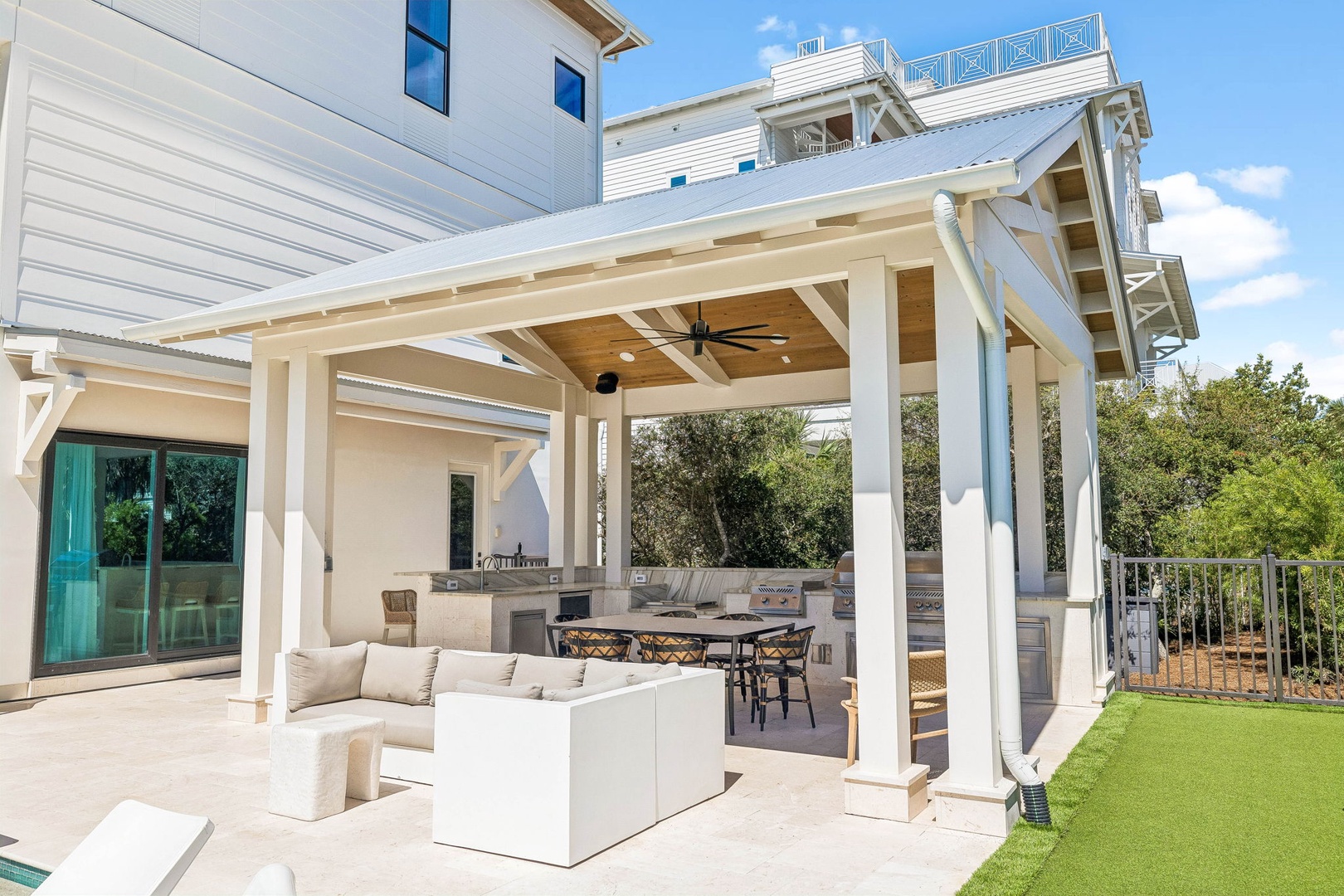 The property offers a beautiful outdoor living space with a covered pergola, modern seating, and entertainment area surrounded by lush greenery, perfect for relaxation and gatherings.