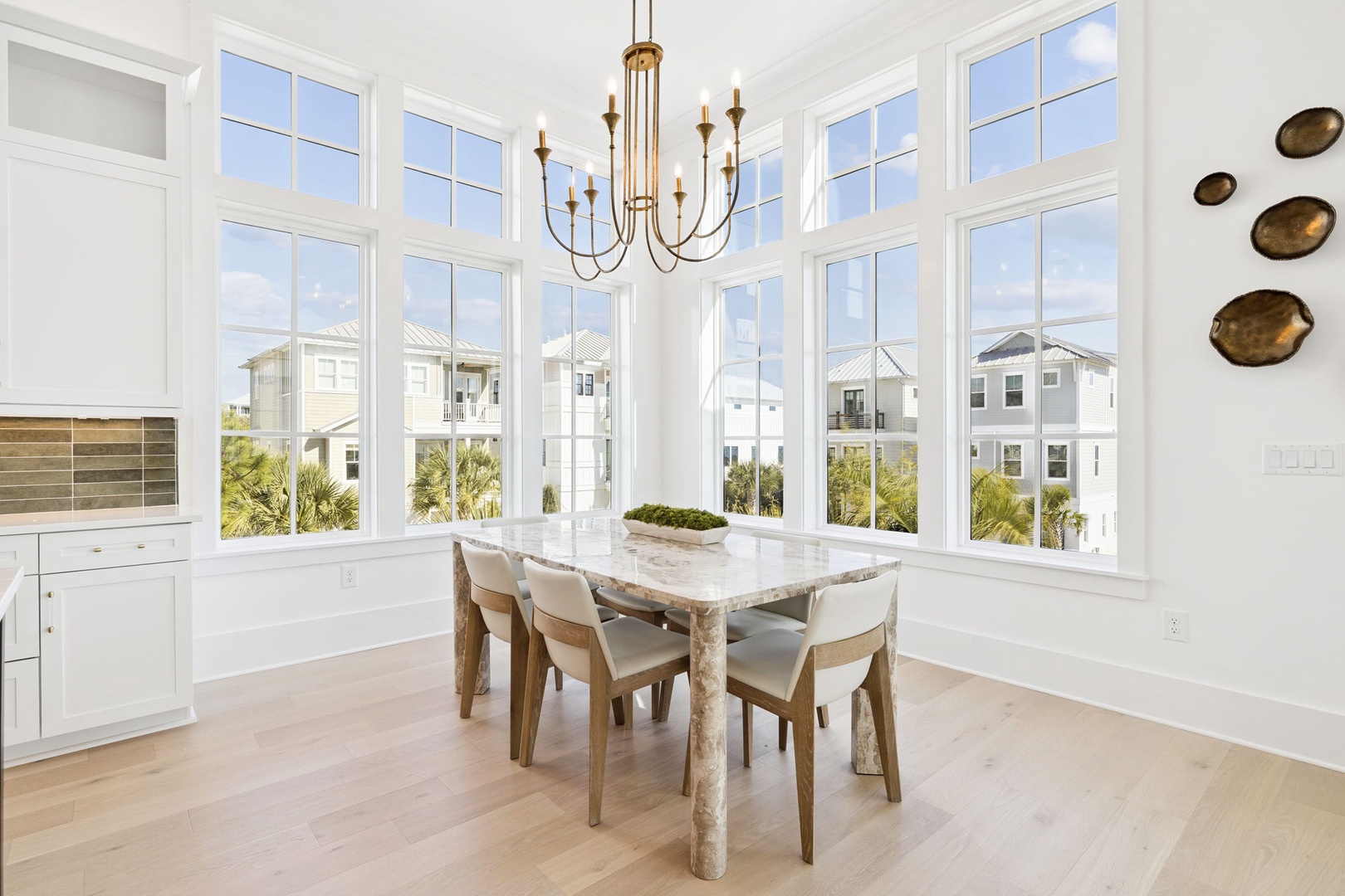 Gather around this elegant marble table in your sun-drenched dining space, where panoramic windows frame coastal views and create the perfect setting for memorable meals.