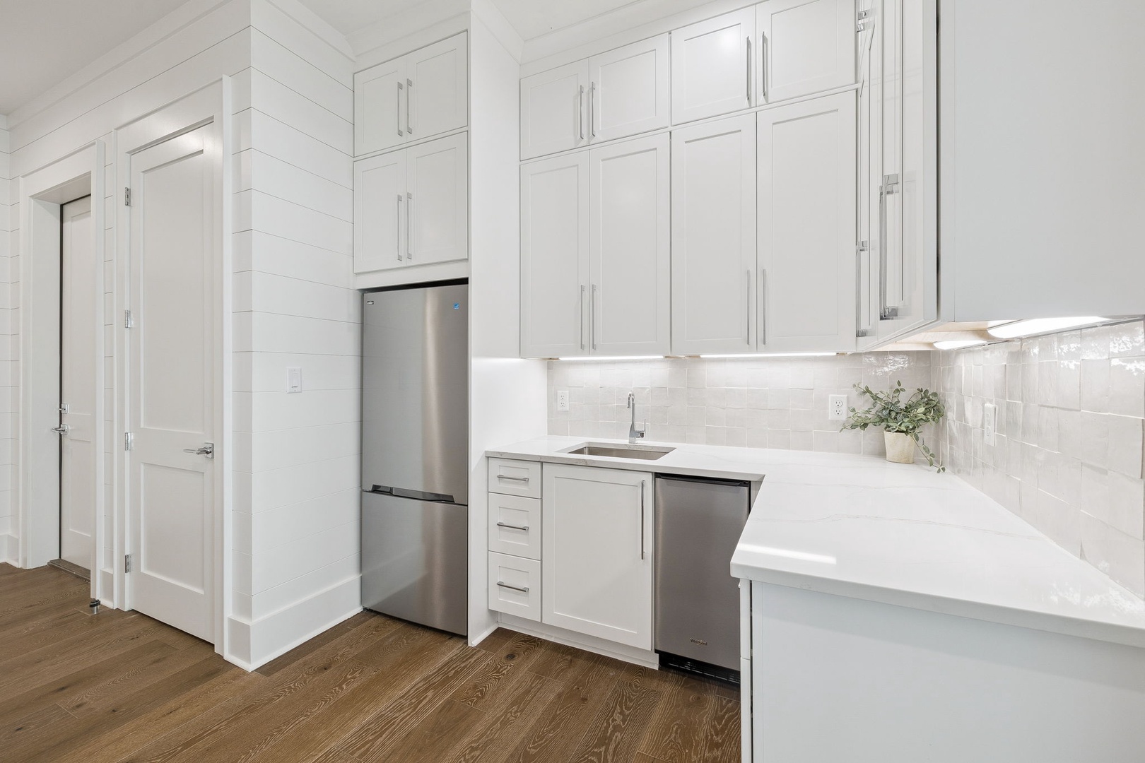 Your pristine white kitchen sparkles with modern appliances and gleaming countertops, perfect for preparing meals in style.