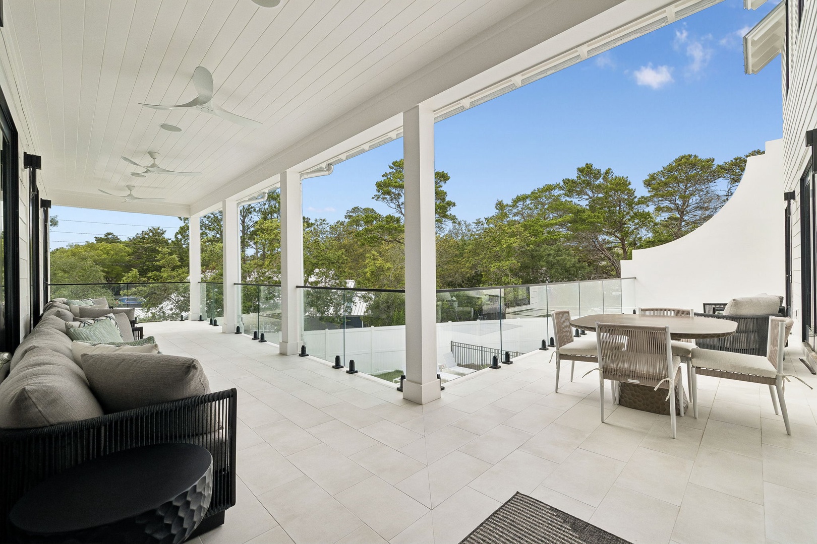 Picture yourself relaxing on this serene covered terrace, sipping morning coffee as gentle breezes drift through. Comfortable seating invites conversation while natural light and lush treetop views create your peaceful outdoor retreat.