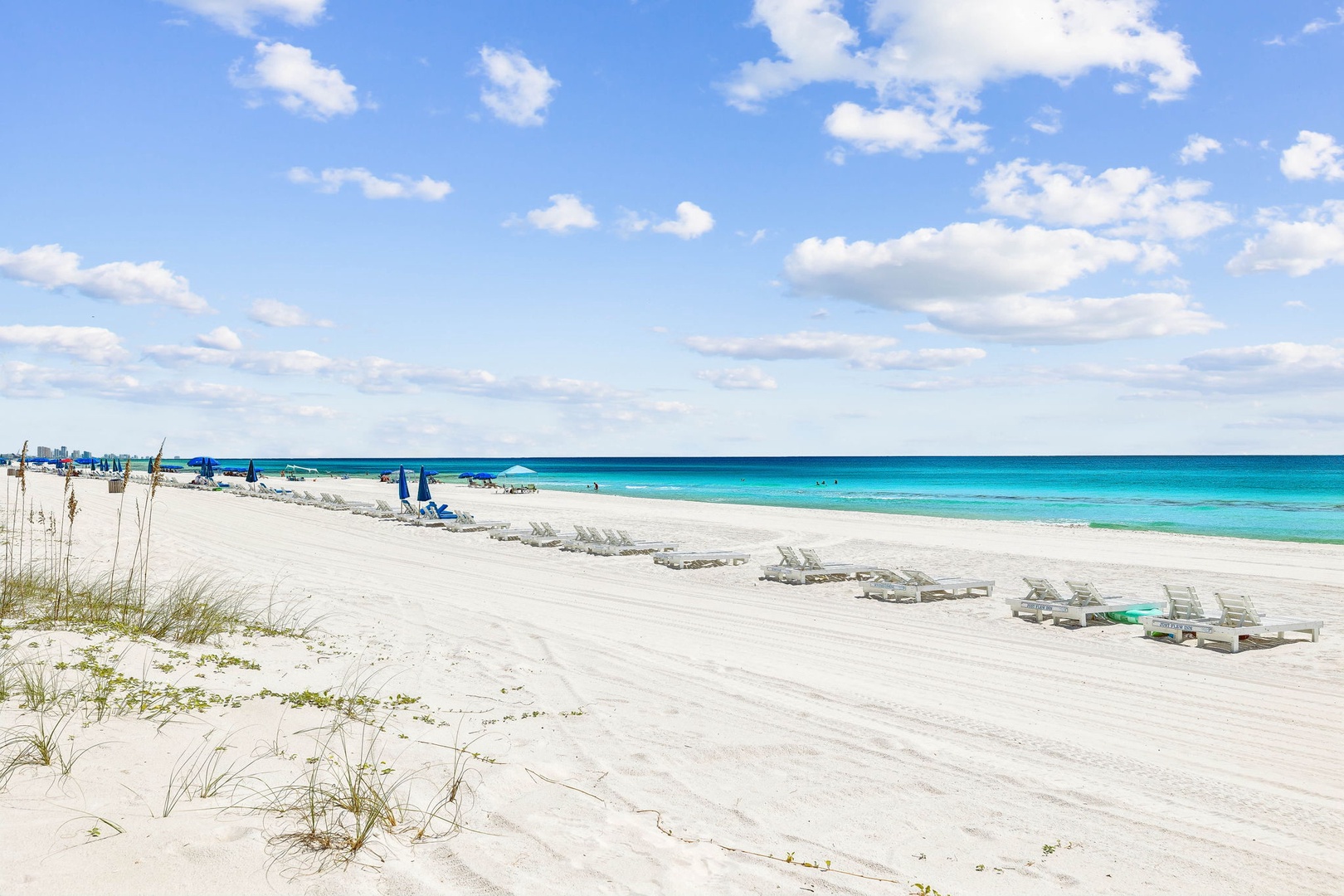 Pristine white sand beach stretches along stunning turquoise waters, offering the perfect coastal escape with lounge chairs ready for your arrival.