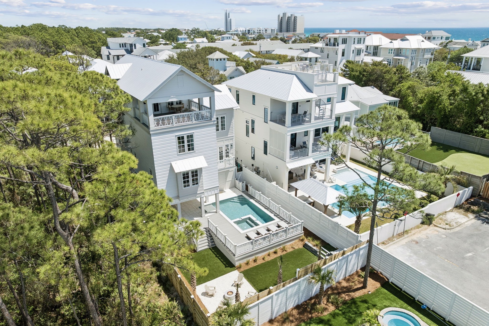 Stunning beachside vacation home featuring private pool, spacious decks, and coastal architecture surrounded by lush trees near the shore.