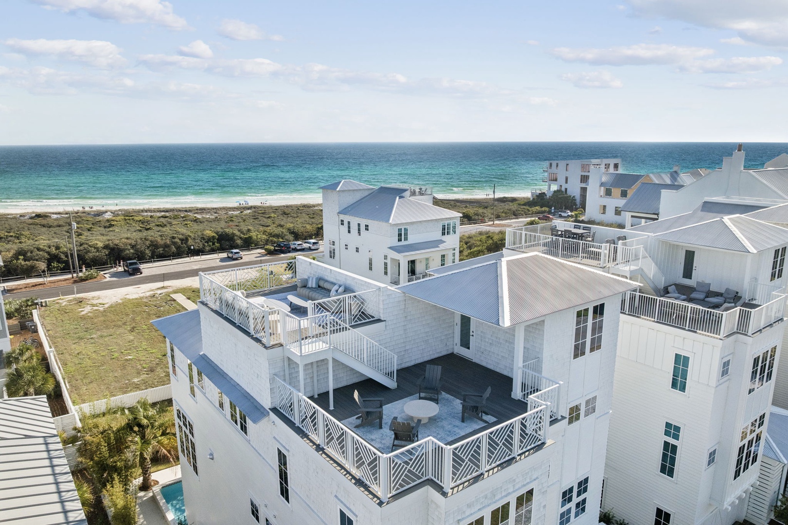 Coastal property complex featuring white architecture with rooftop terraces and beach access nearby.